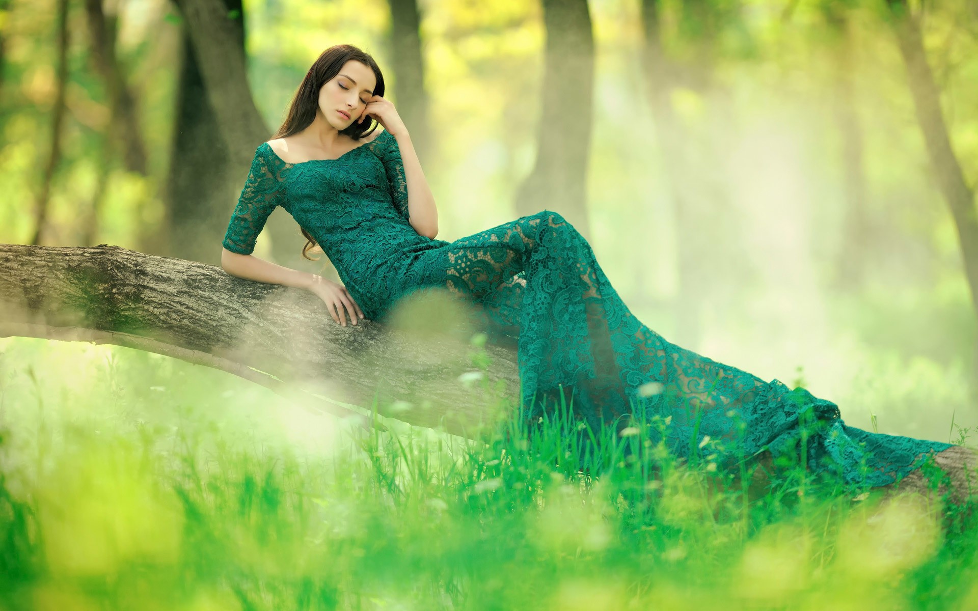 Woman in a green lace dress sitting on a log HD Wallpaper