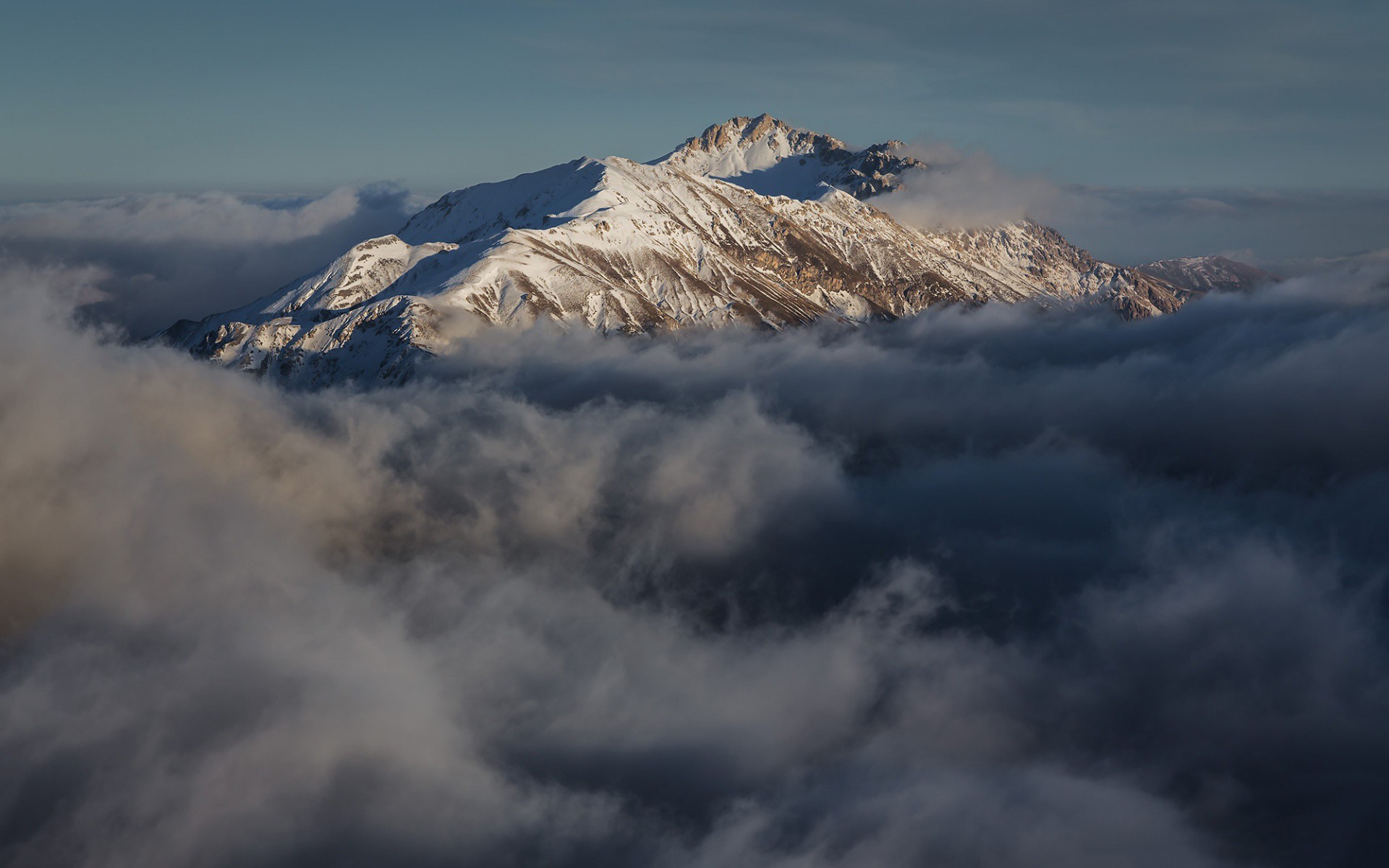 Snow-capped mountains emerge from clouds HD Wallpaper