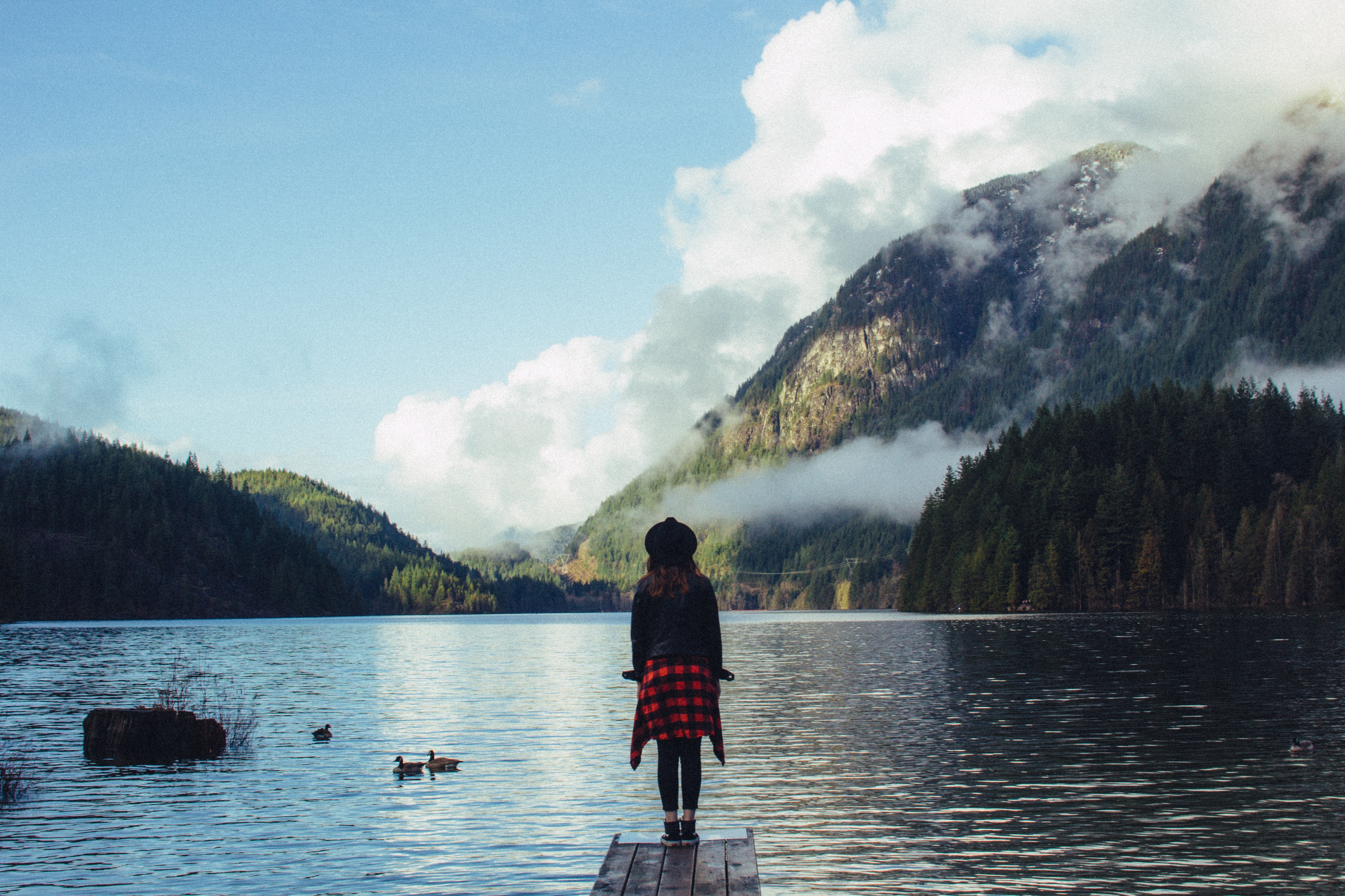 Woman on a dock overlooking a mountain lake HD Wallpaper