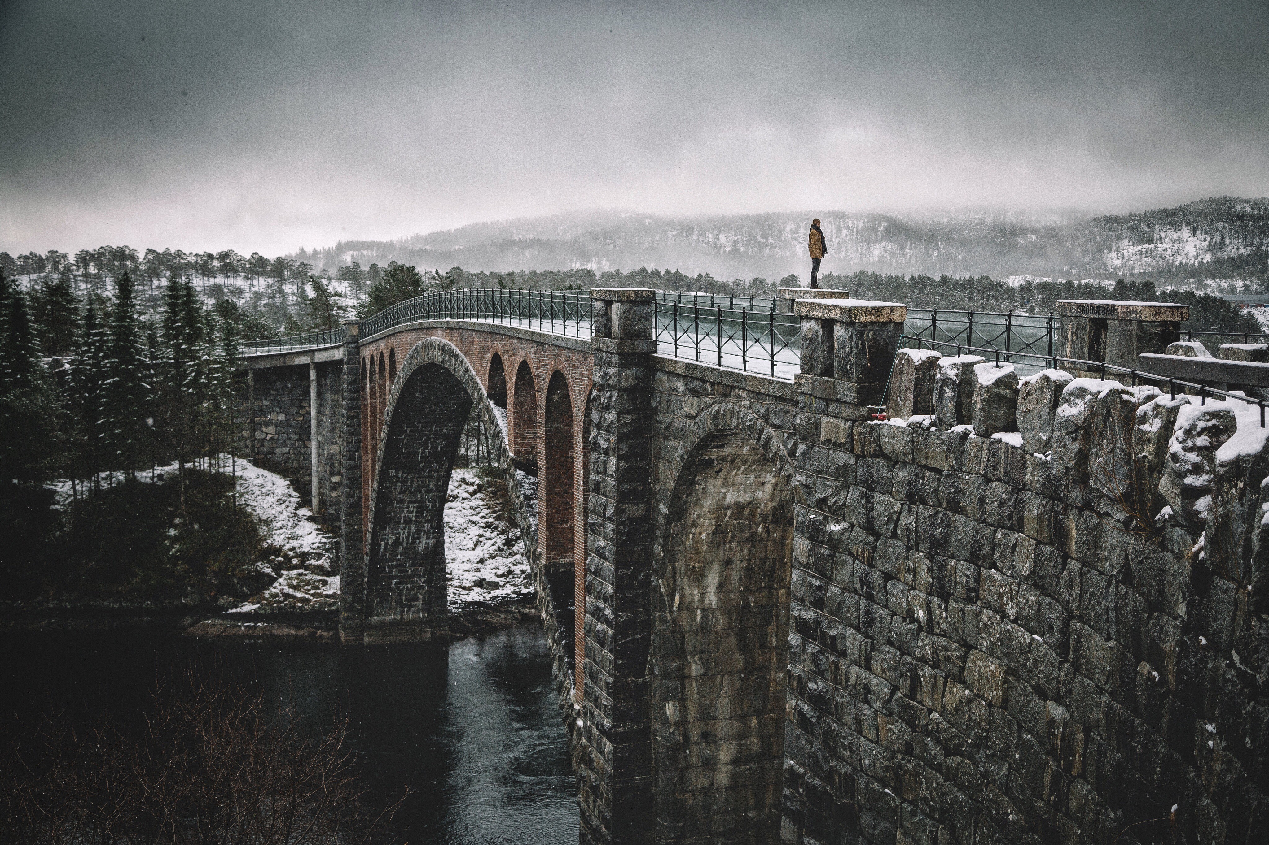 Man on a stone bridge in Norway during winter HD Wallpaper