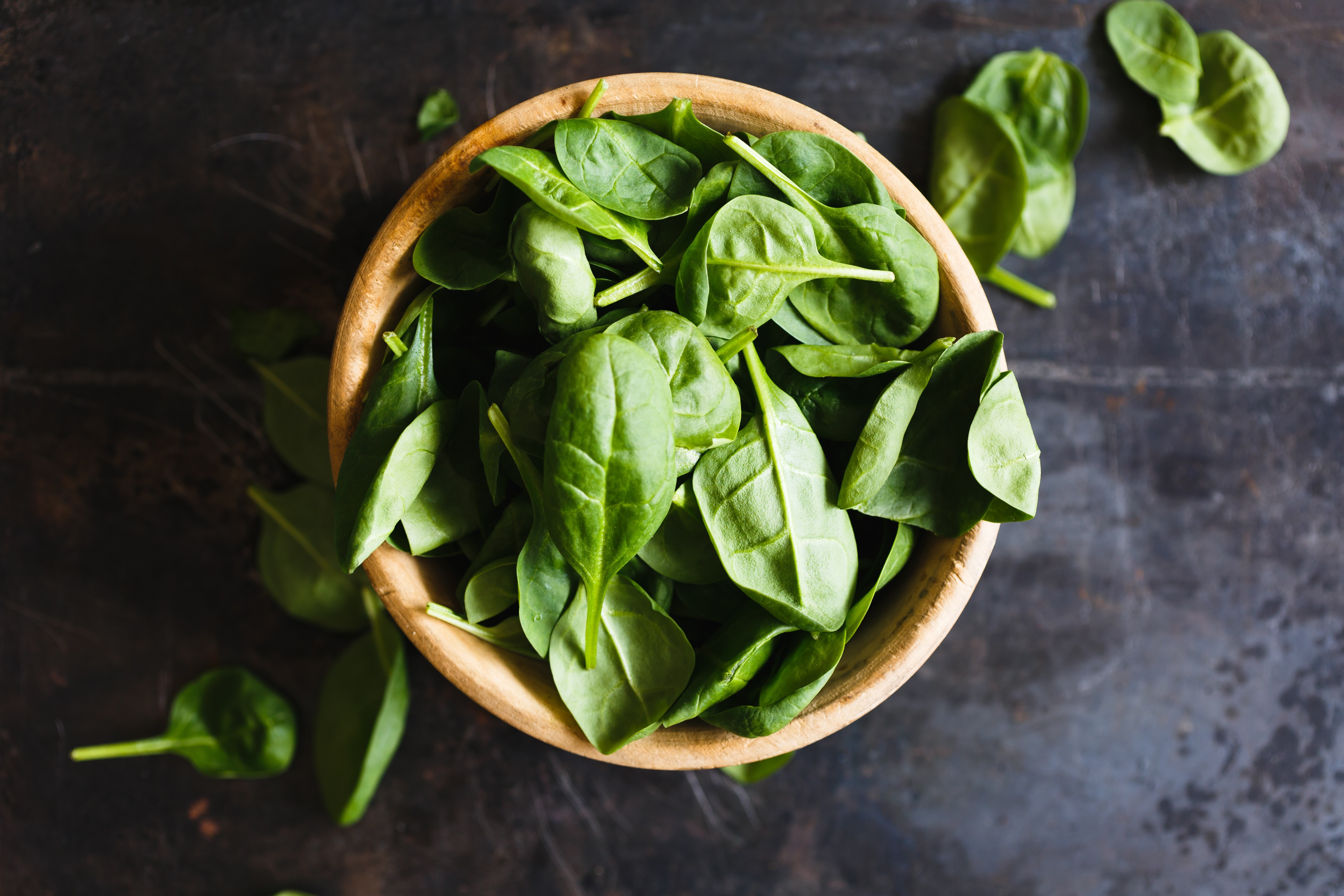 Bowl of fresh spinach leaves on a dark surface HD Wallpaper