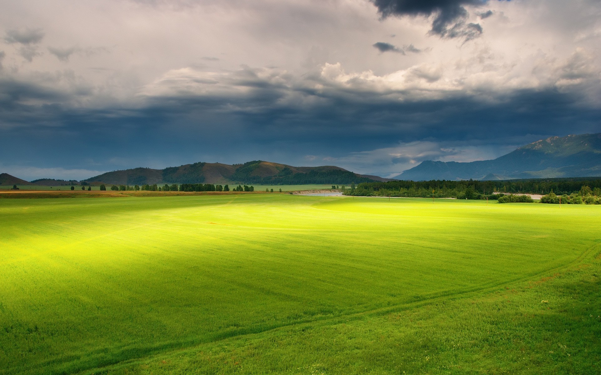 Green field with mountains and stormy clouds HD Wallpaper