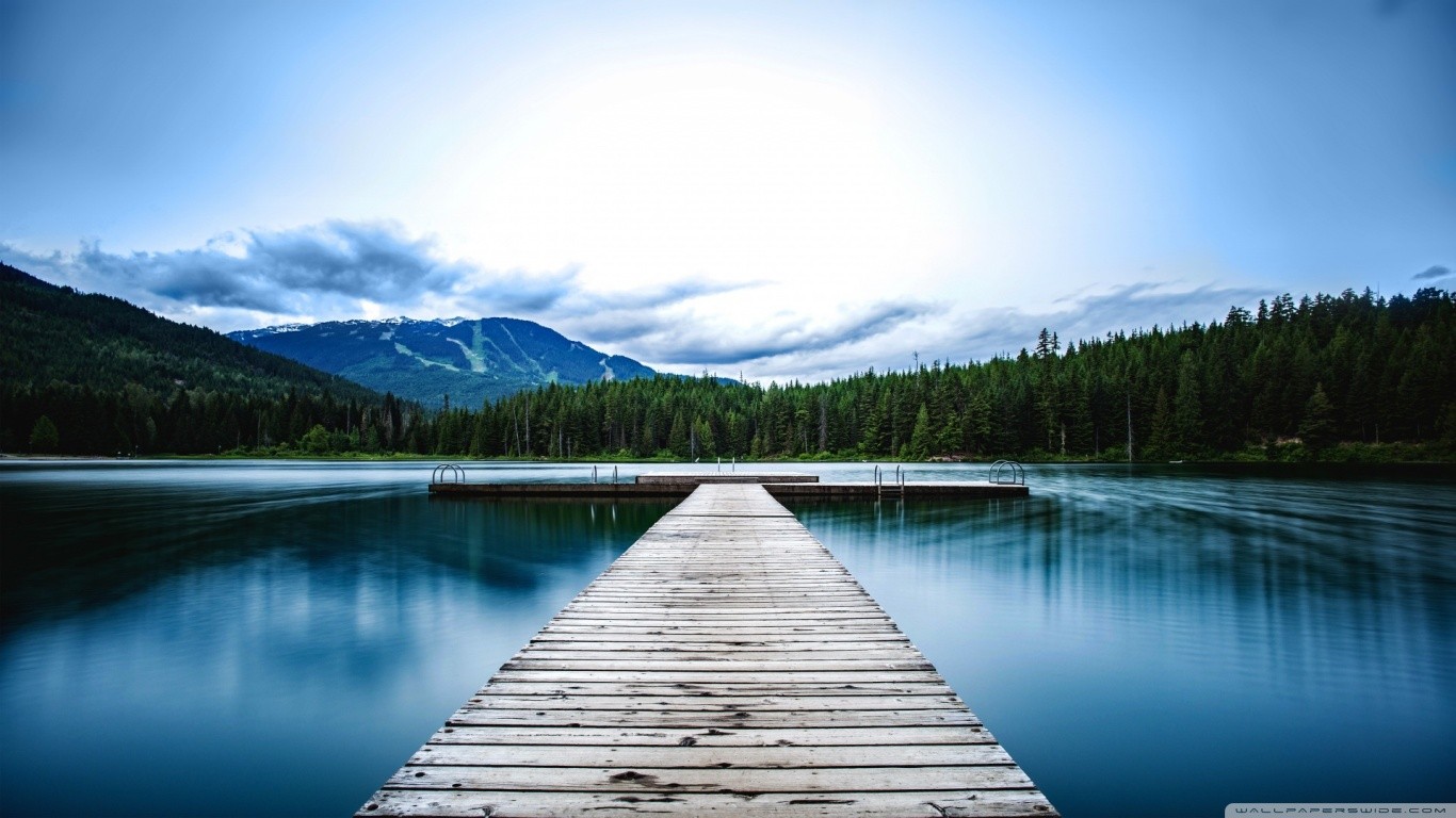 Wooden pier on a calm lake with mountains and forest HD Wallpaper