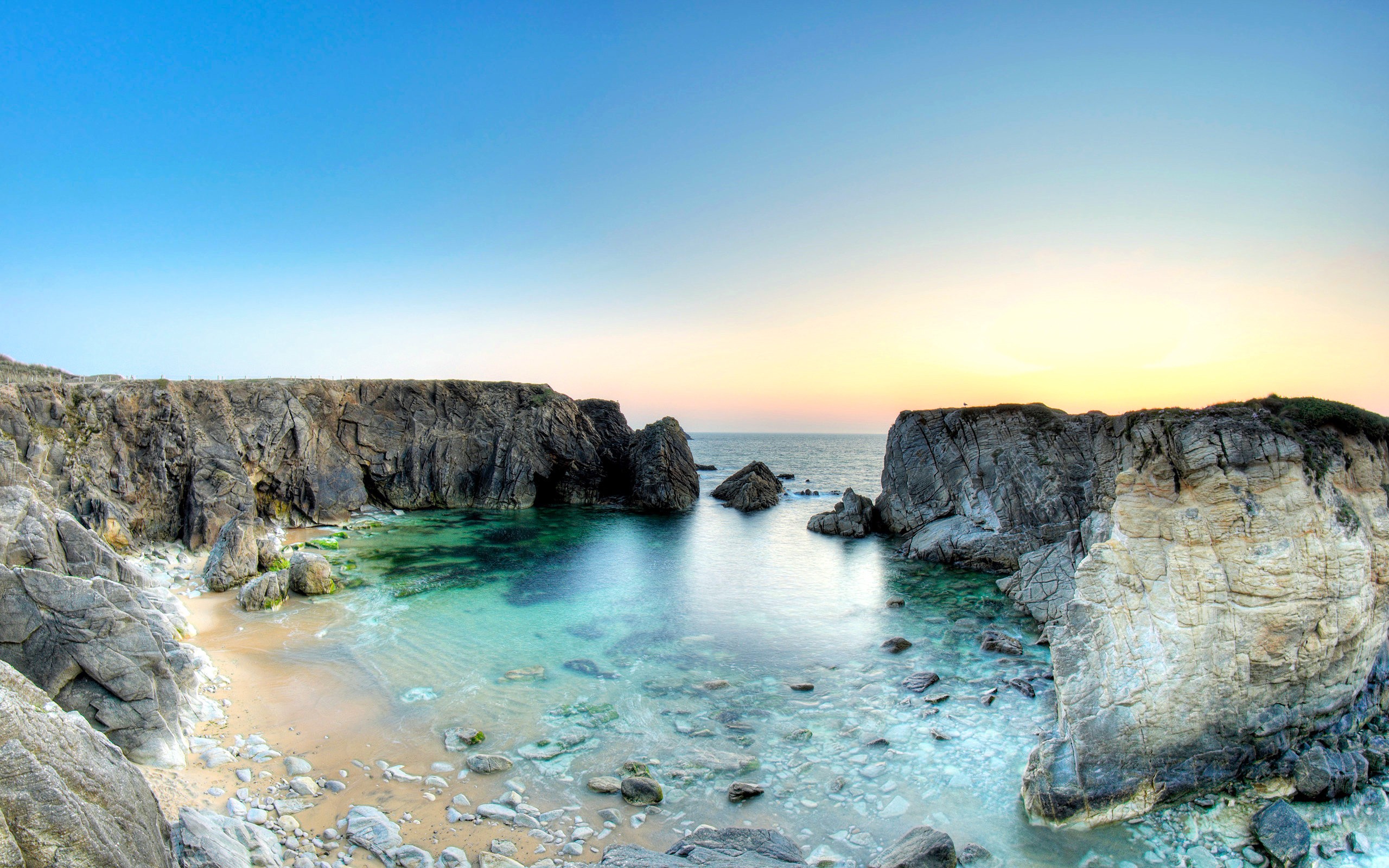 Rocky cove with clear turquoise water at sunset HD Wallpaper
