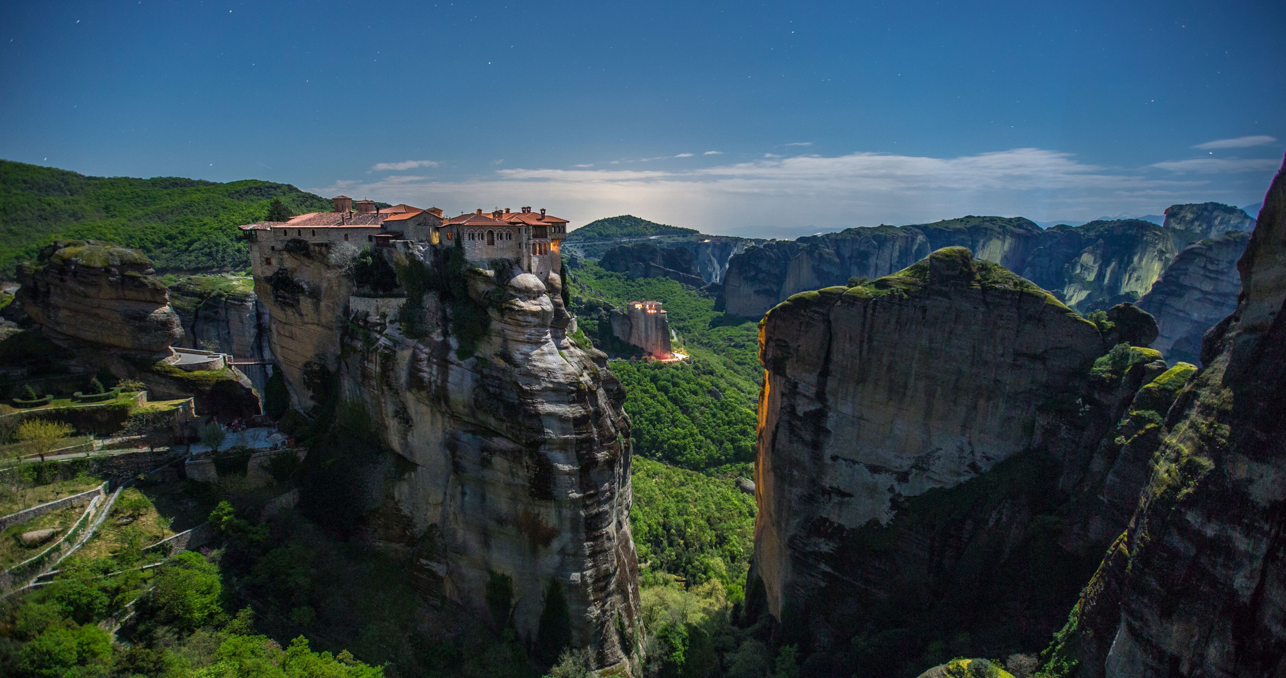 Meteora monasteries perched on rock formations under a starry sky HD Wallpaper