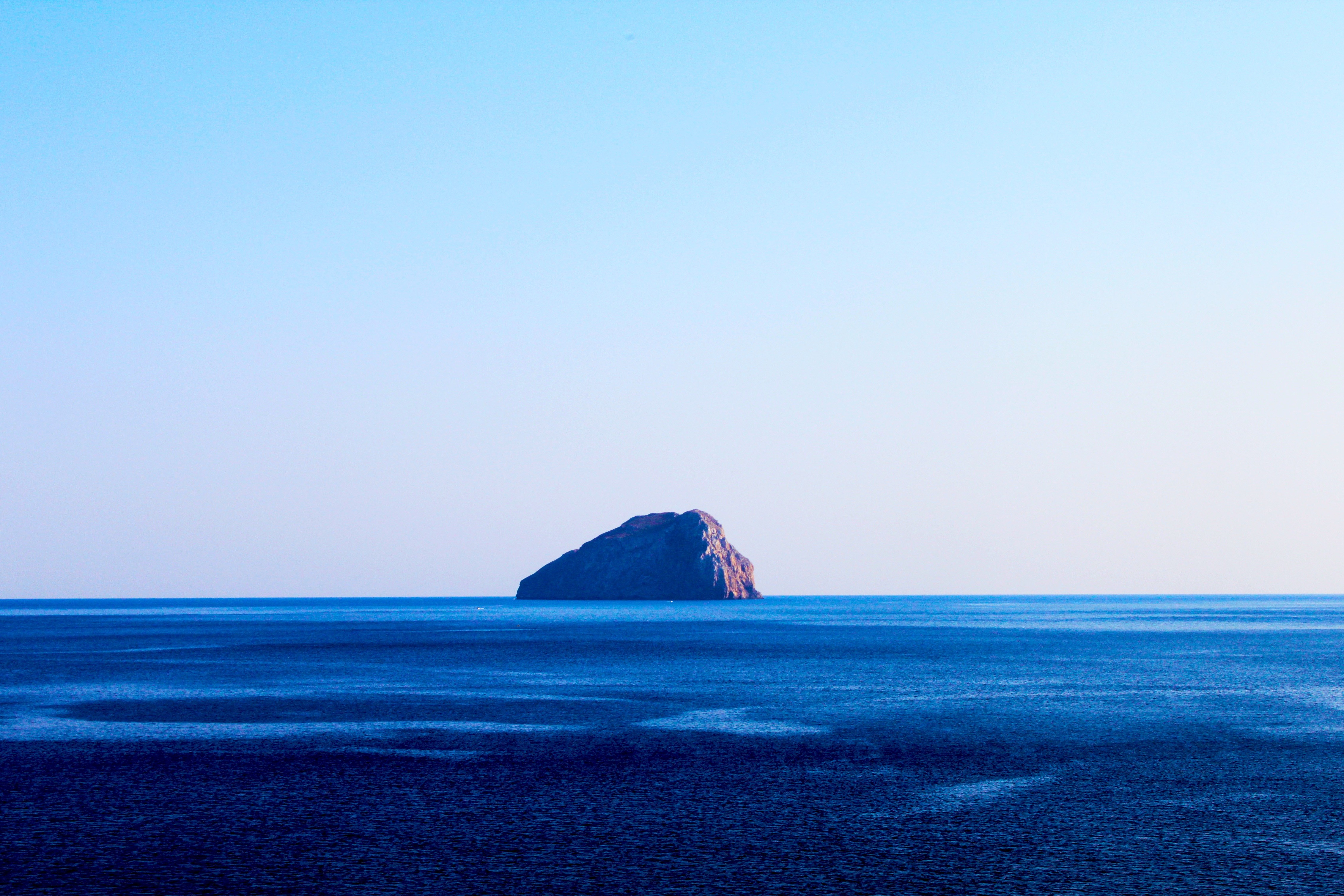 Island in the vast blue sea under a clear sky HD Wallpaper