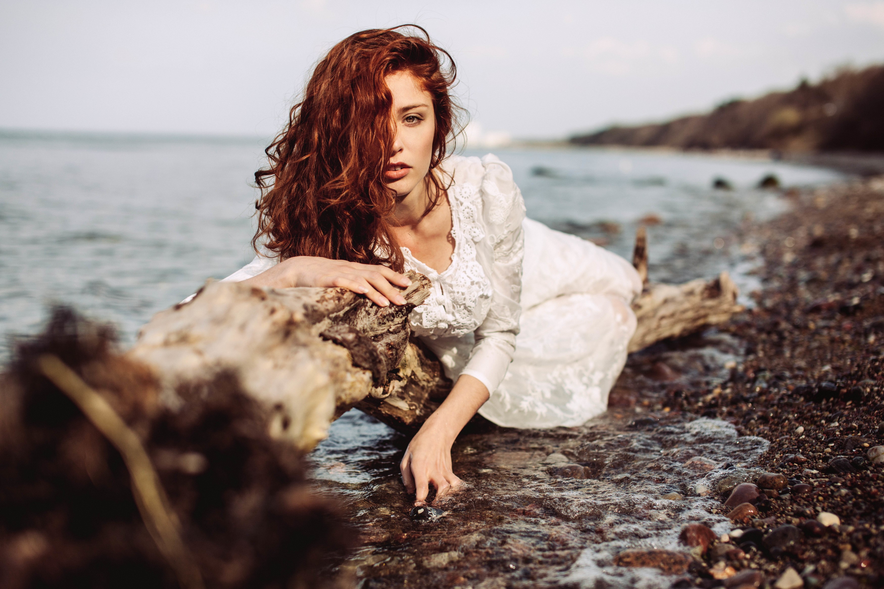 Redhead woman in white dress on a log by the water HD Wallpaper
