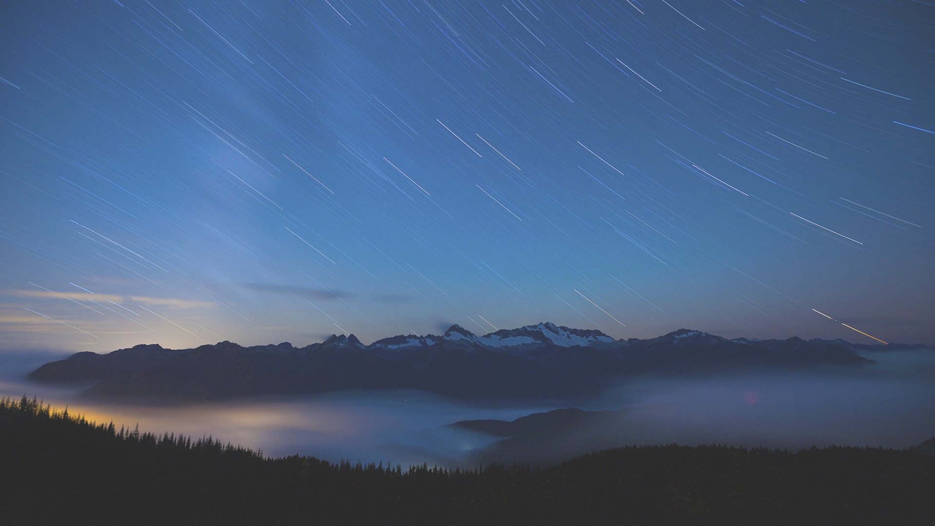 Star trails over misty mountains at night HD Wallpaper
