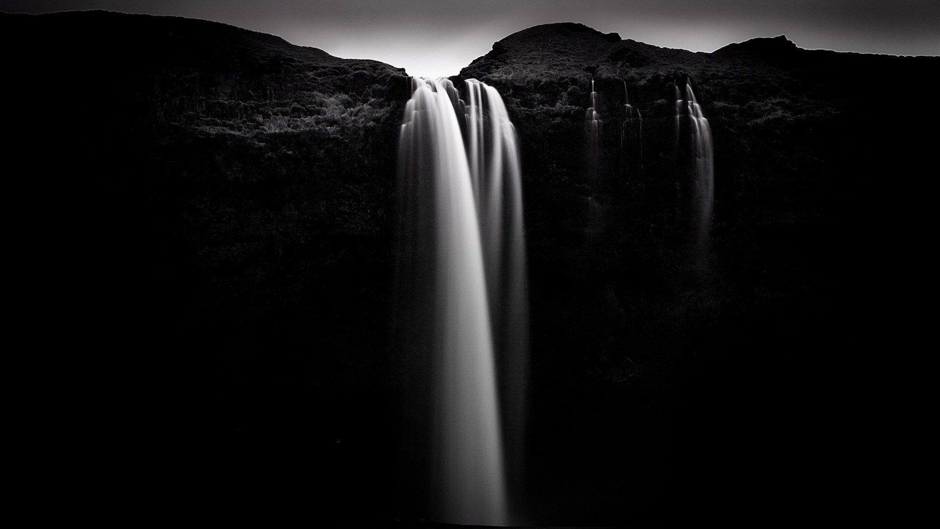 Monochrome long exposure of a waterfall cascading over rocks HD Wallpaper