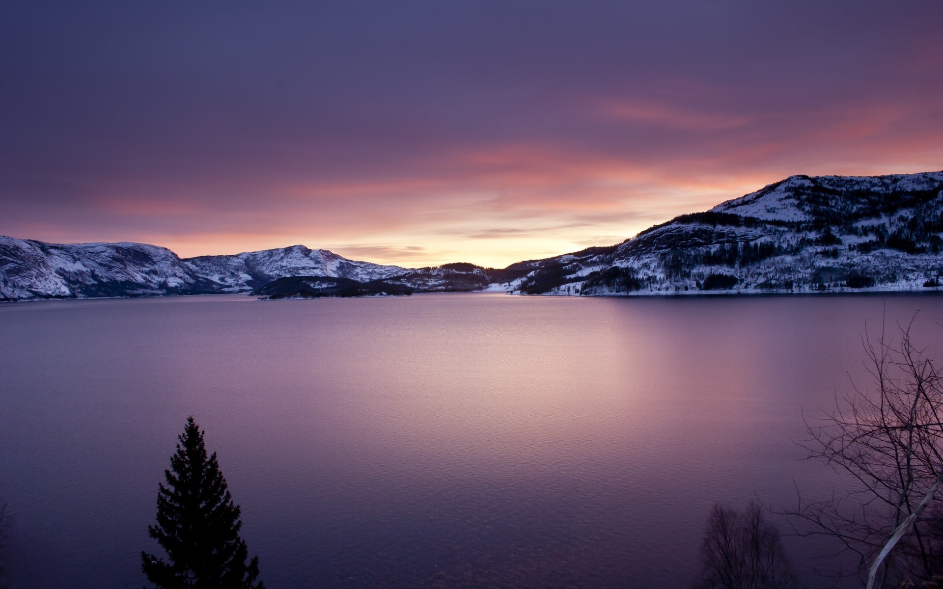 Snow-capped mountains surround a calm lake at sunset HD Wallpaper