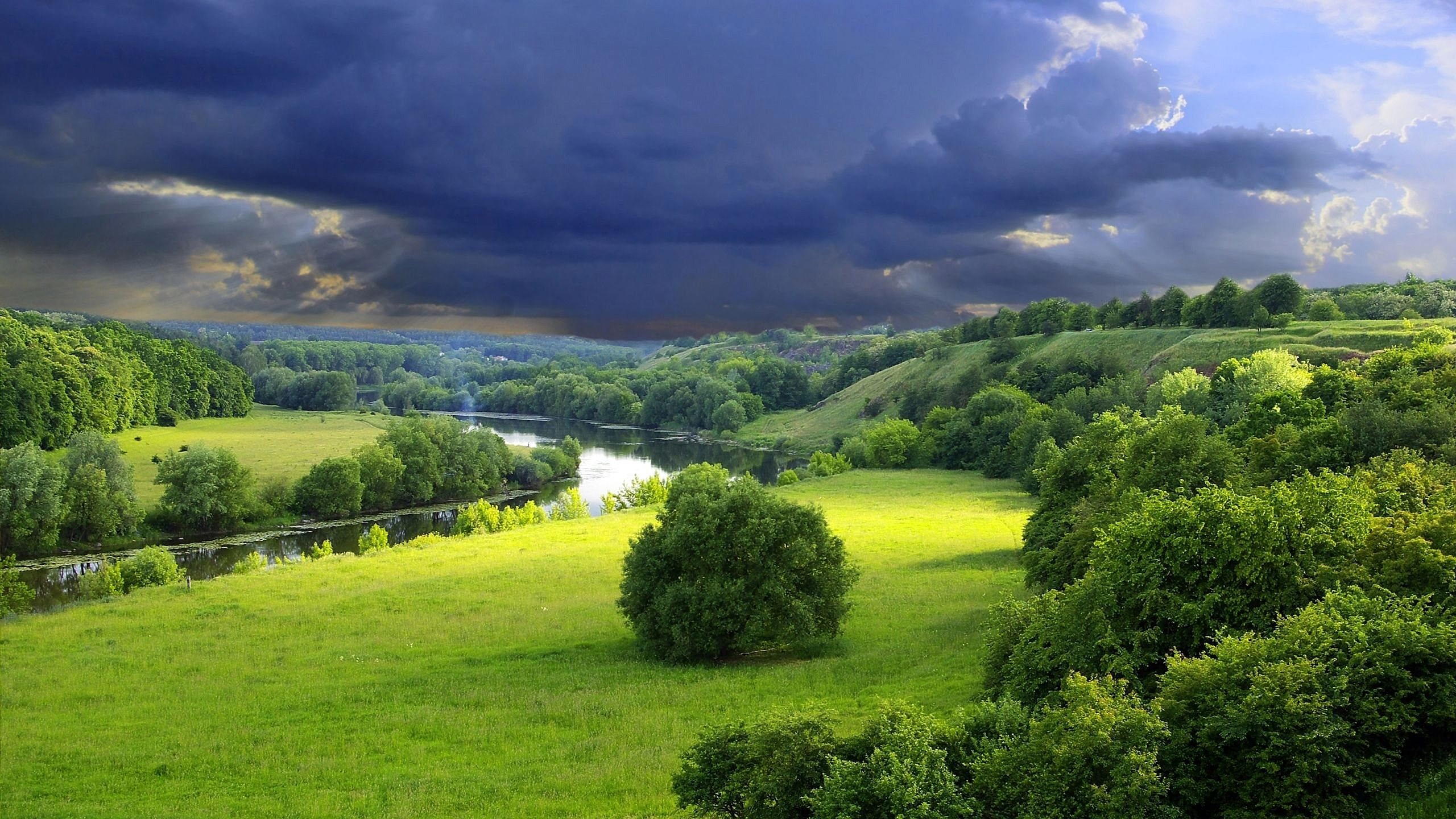 Stormy sky over a river landscape with green hills HD Wallpaper