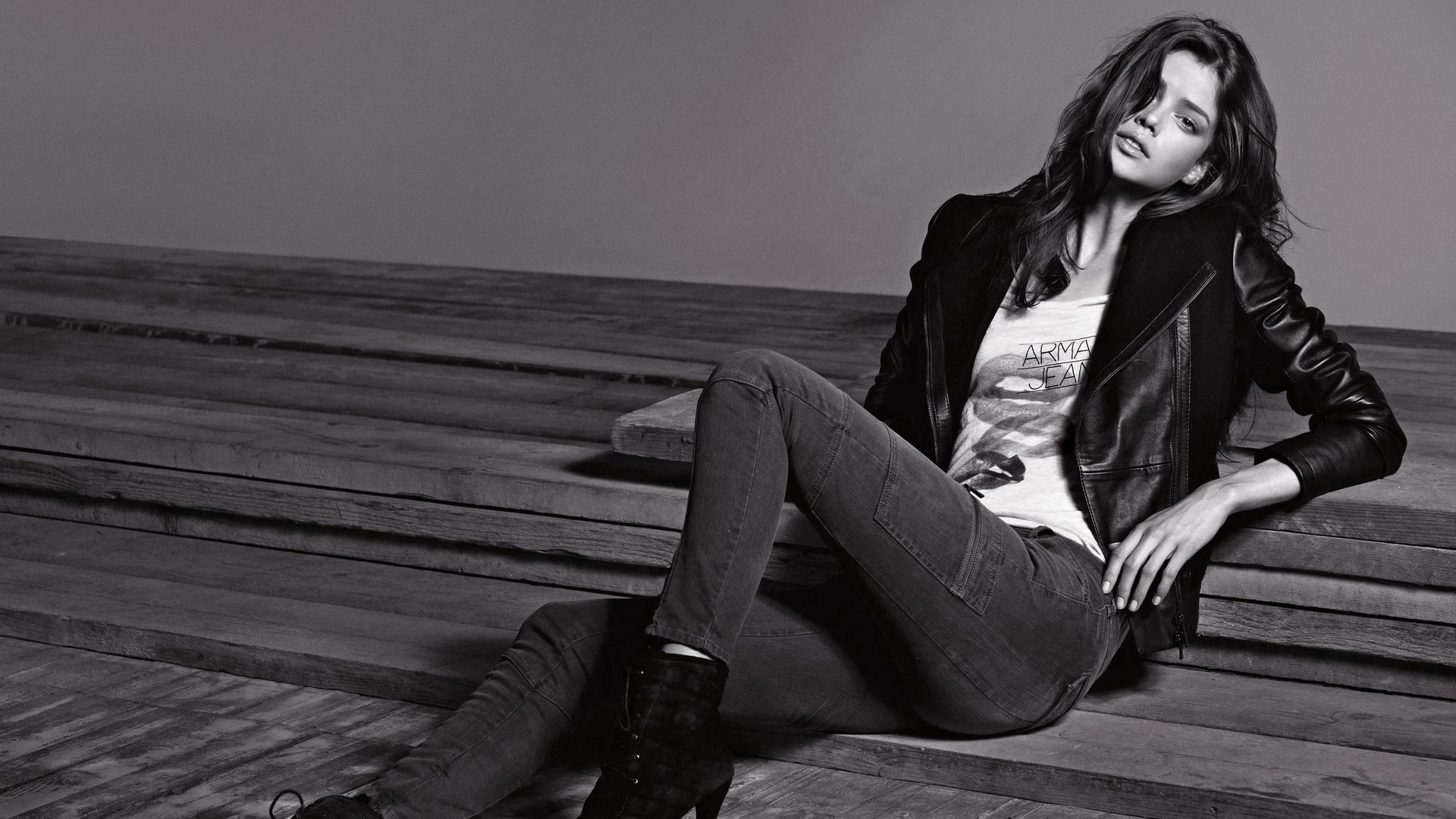Woman in leather jacket and jeans sitting on wooden steps HD Wallpaper