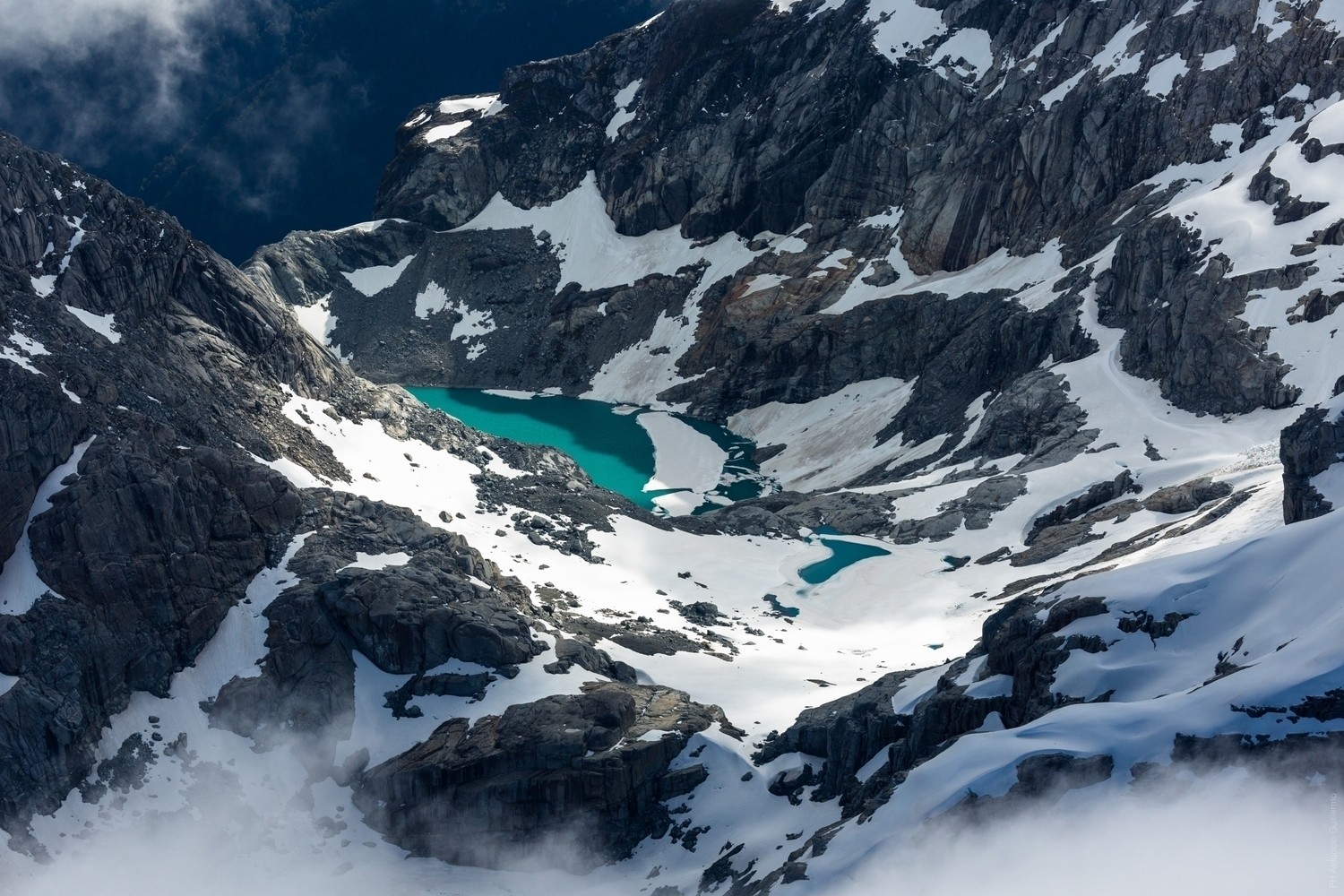 Turquoise lake nestled in snowy mountains HD Wallpaper