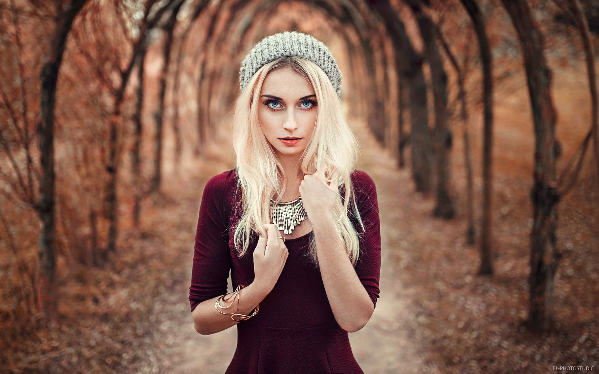 Blonde woman wearing a beanie and dress in a forest HD Wallpaper