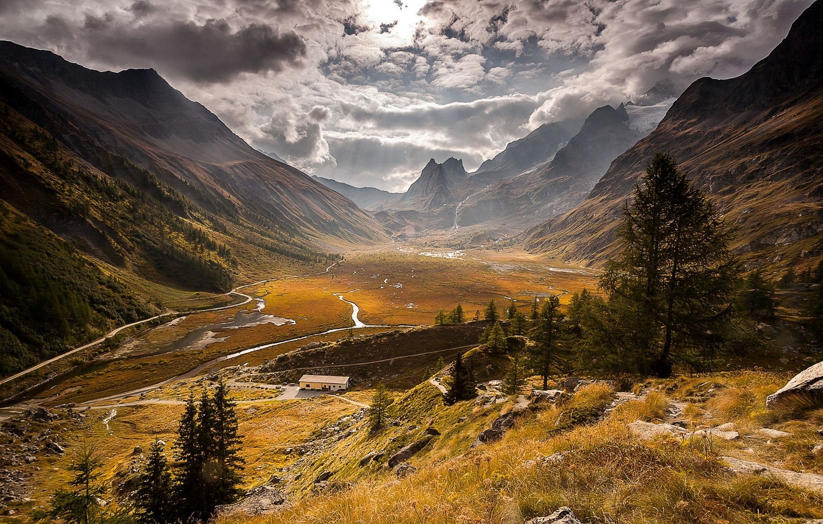 Valley in the Alps with a road and a building HD Wallpaper