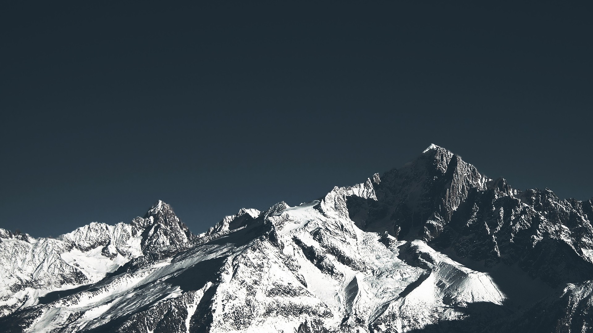Snow-covered mountains under a dark sky HD Wallpaper
