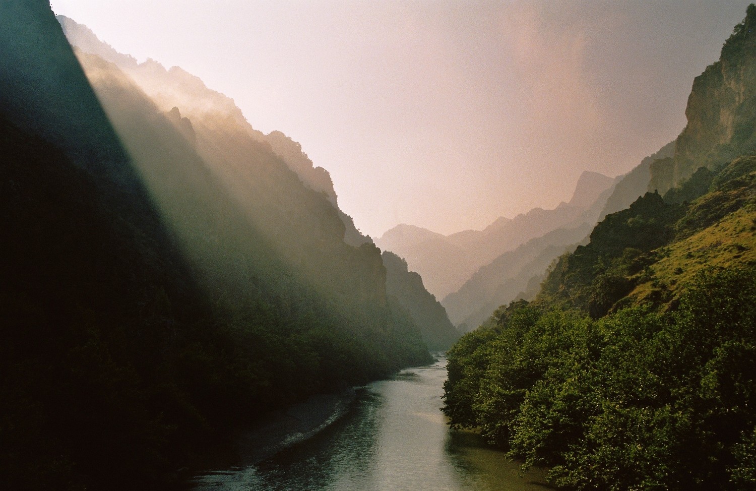 Sun rays over a river valley with mountains and trees HD Wallpaper