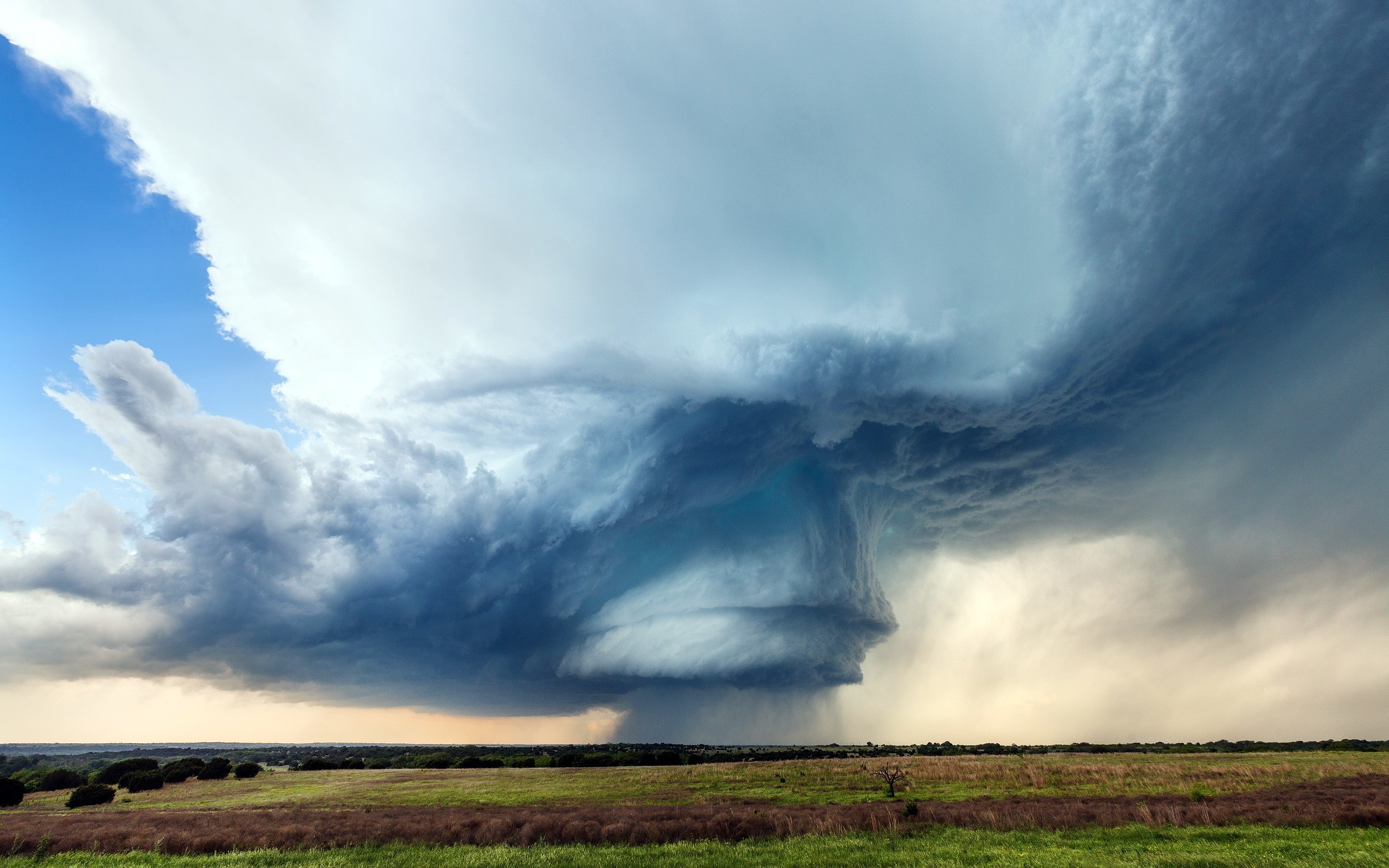 Dramatic storm clouds over a grassy field HD Wallpaper