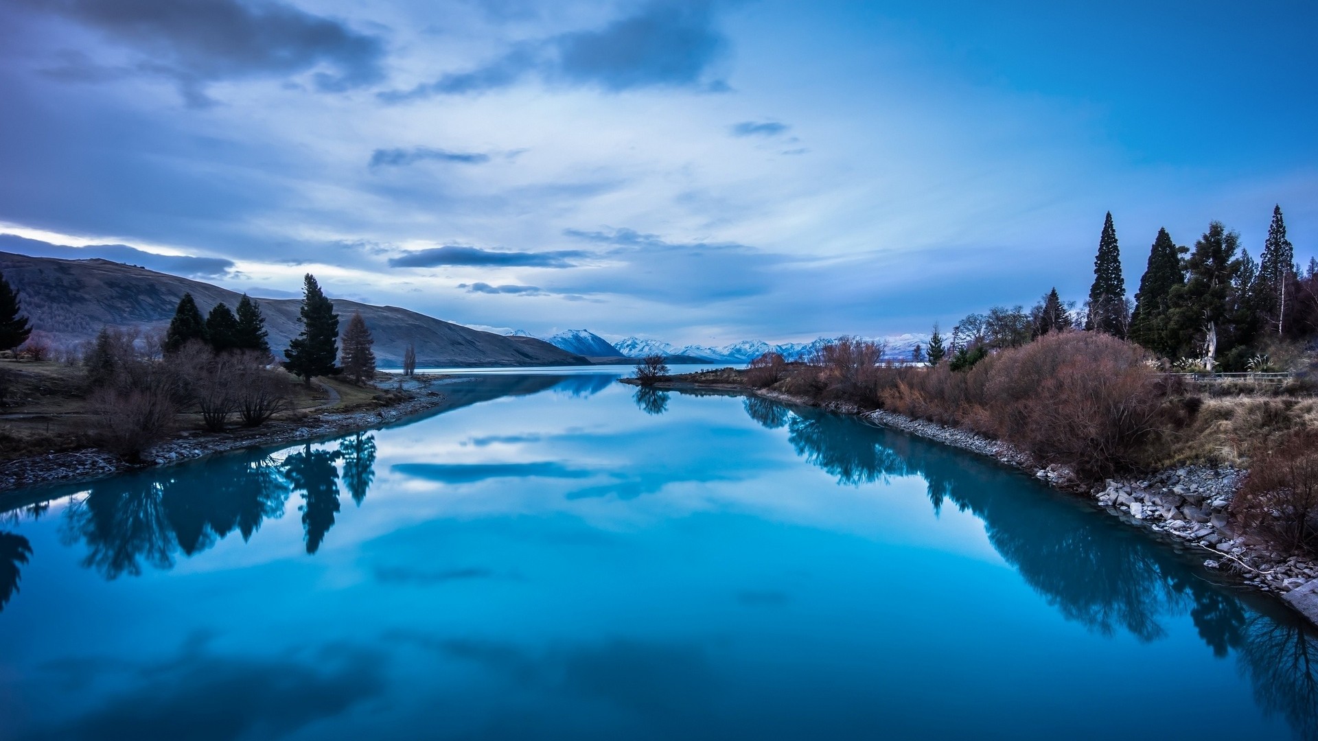 Blue lake with reflections and mountains under cloudy sky HD Wallpaper