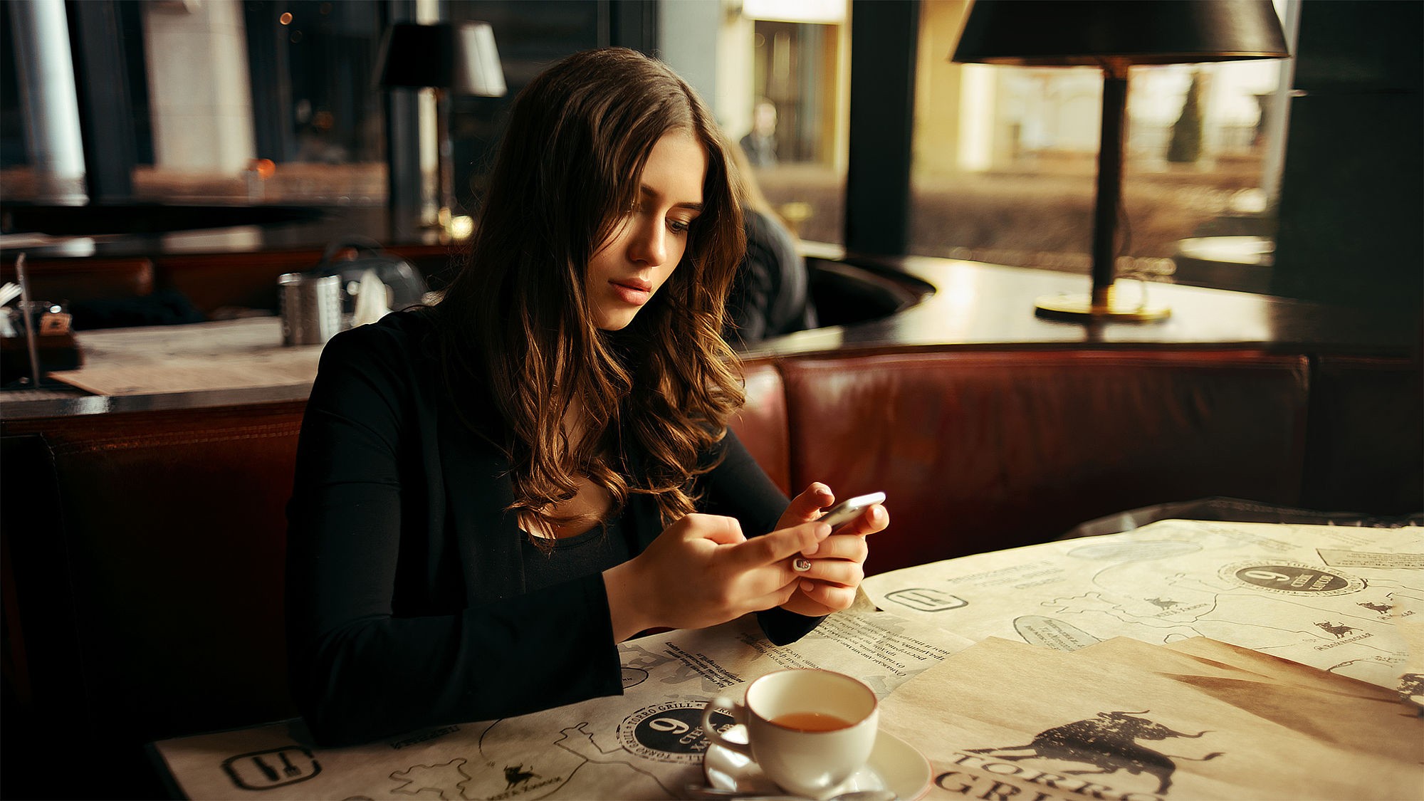 Woman using a smartphone at a table with coffee HD Wallpaper