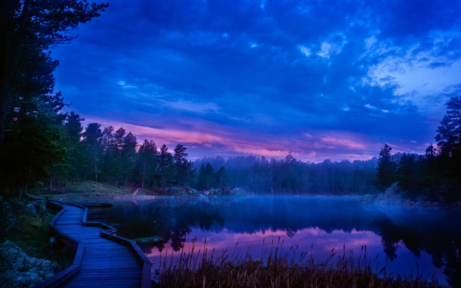 Wooden boardwalk by a misty lake at twilight HD Wallpaper