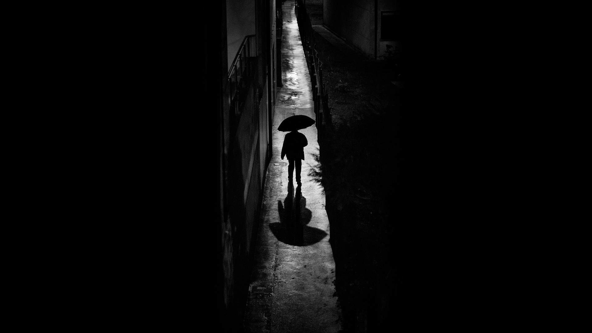 Silhouette of a person with an umbrella walking at night HD Wallpaper