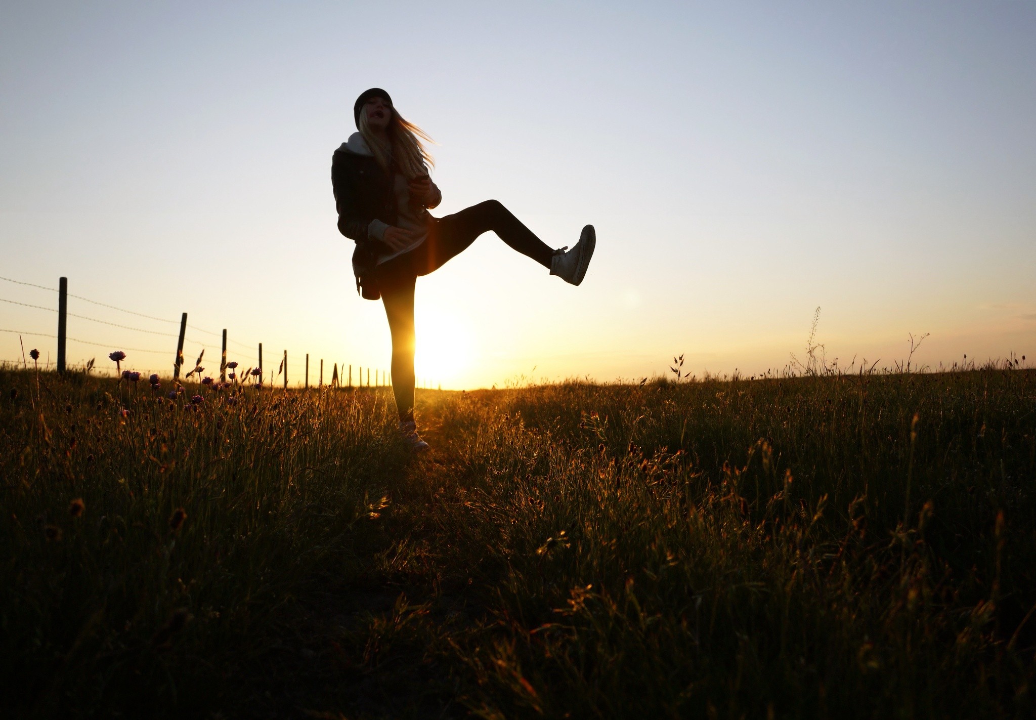 Woman kicking leg up in a field at sunset HD Wallpaper
