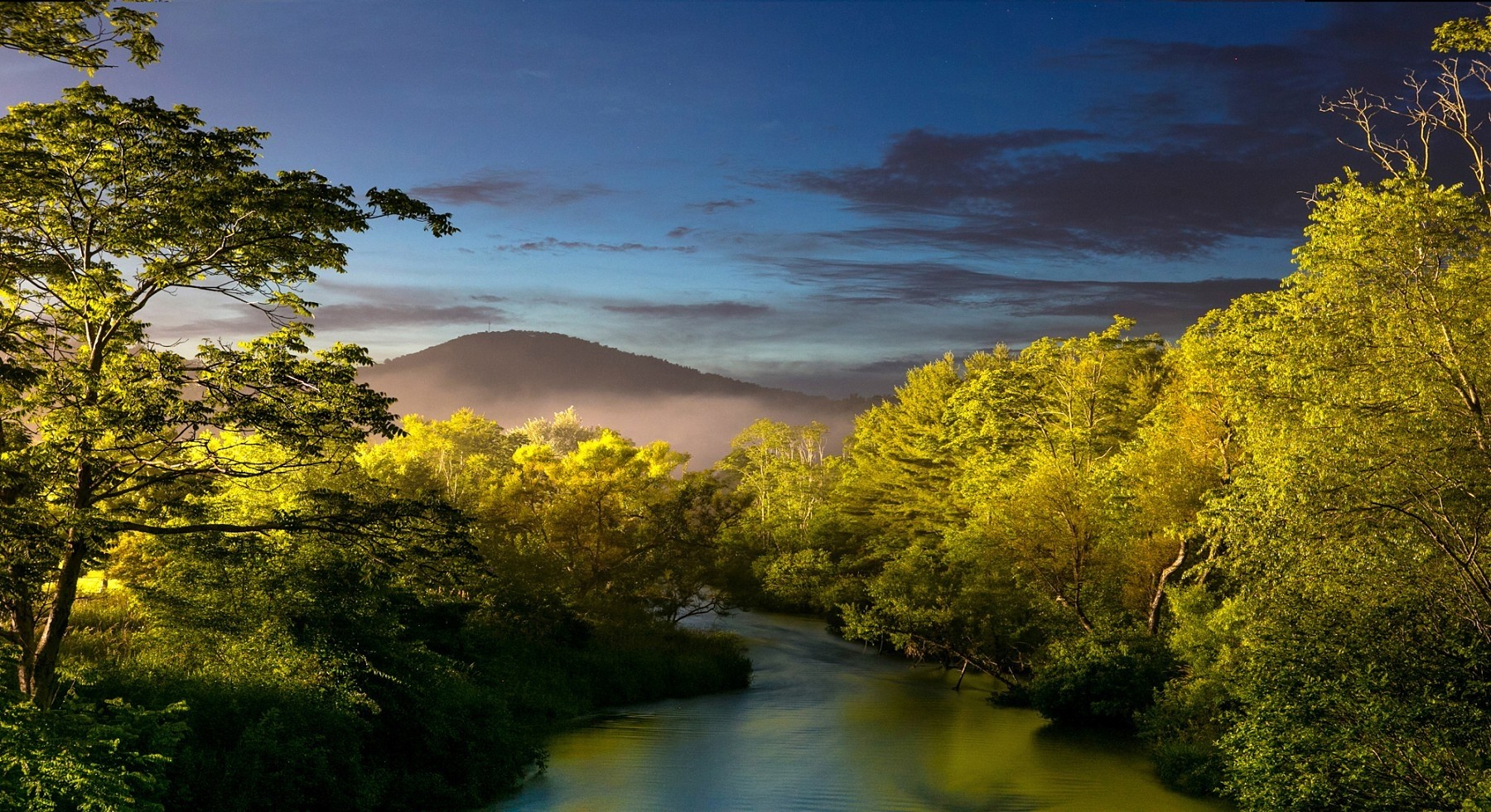 River flowing through trees with hills in the background HD Wallpaper
