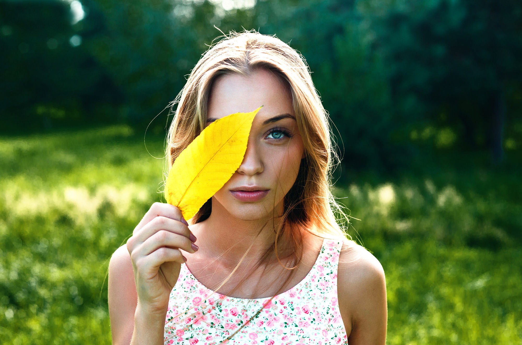 Woman holding a yellow leaf in front of her eye HD Wallpaper