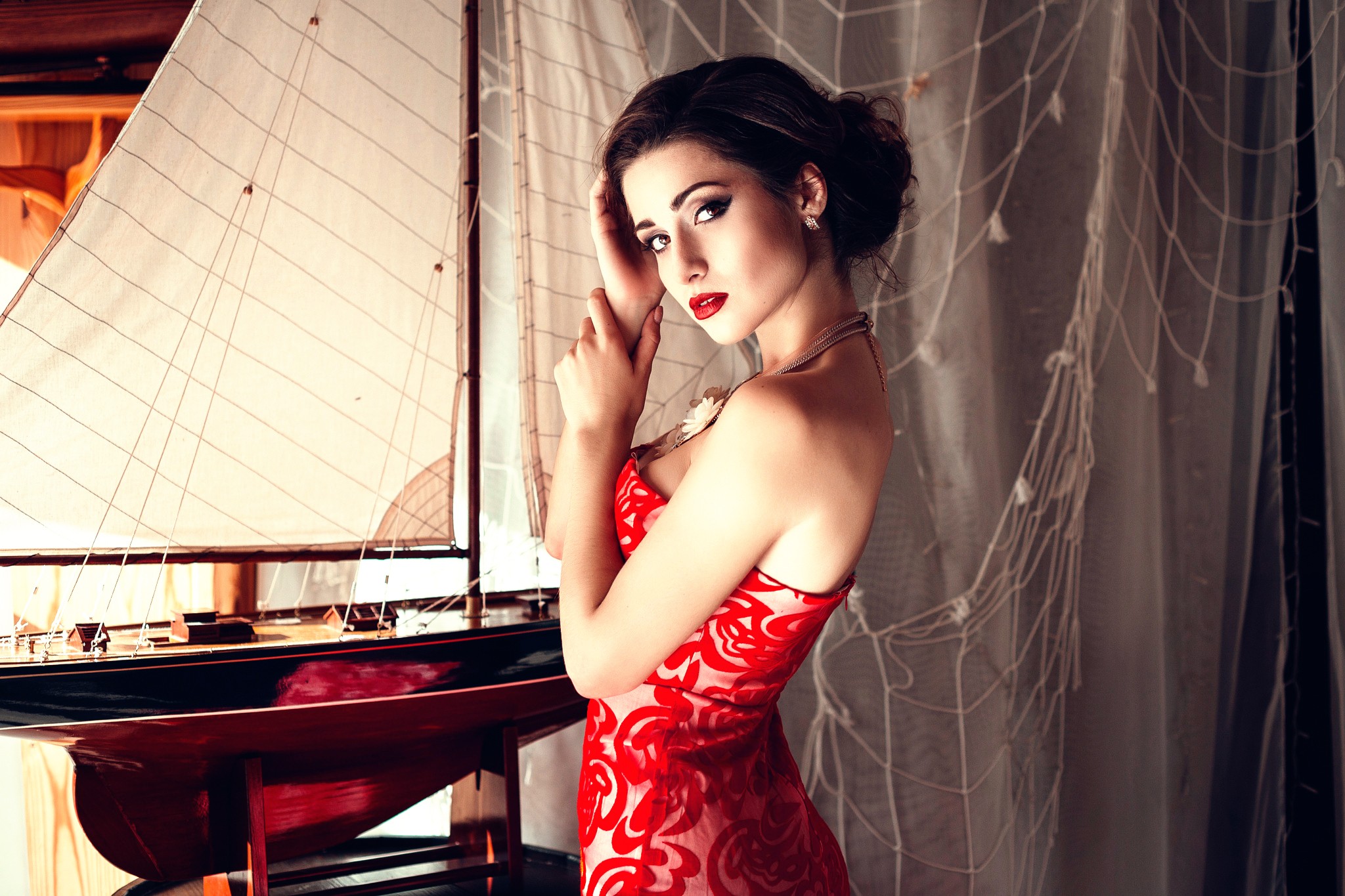 Woman in red dress posing by a model sailboat HD Wallpaper