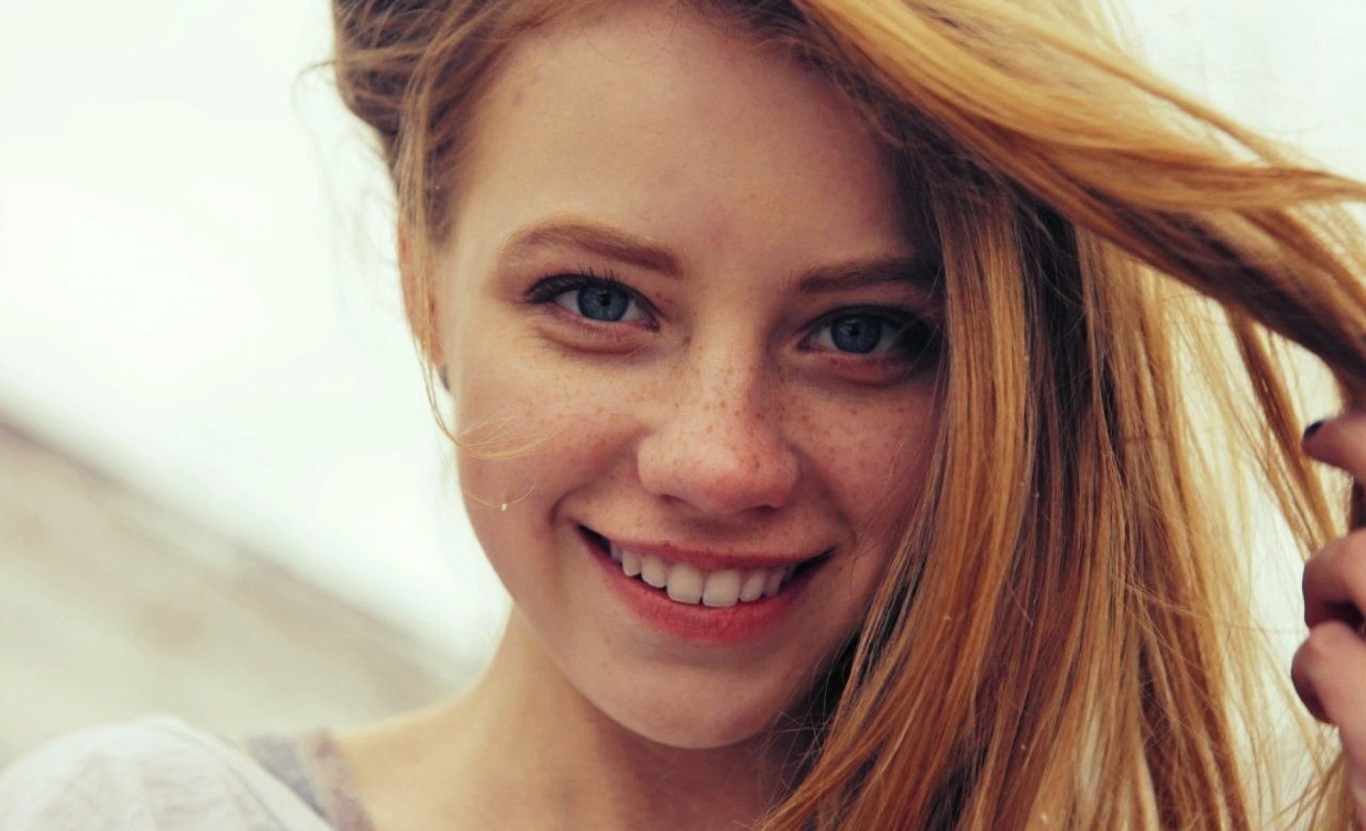 Young woman with freckles and blue eyes smiling HD Wallpaper