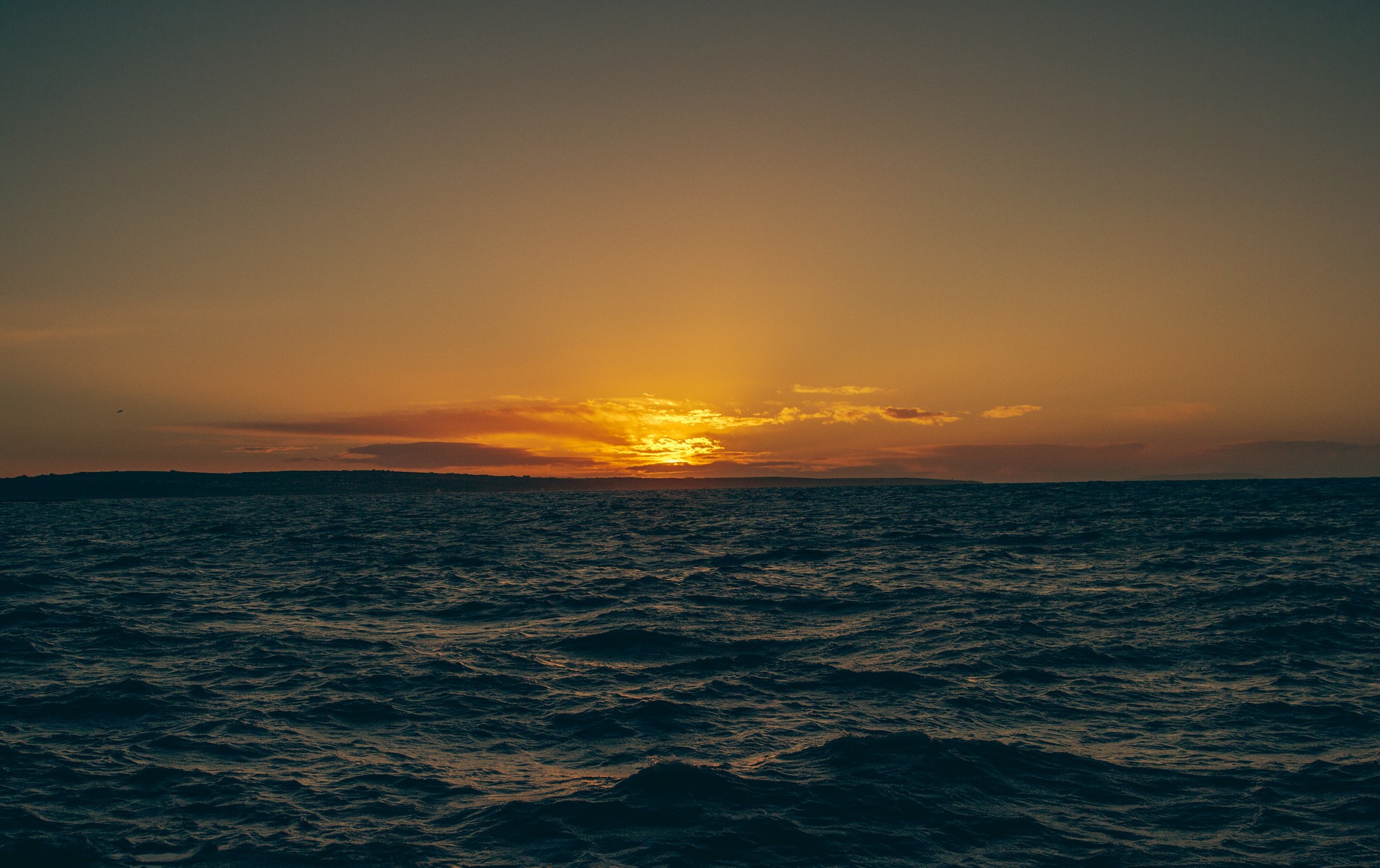 Sunset over the sea with distant land HD Wallpaper