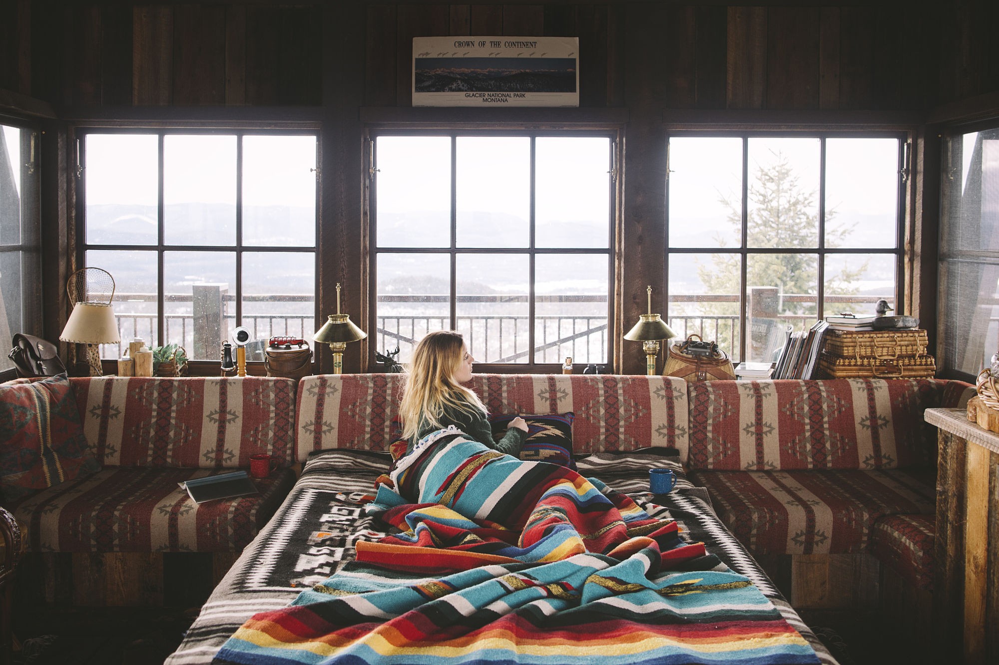 Woman relaxing in a rustic cabin with mountain views HD Wallpaper