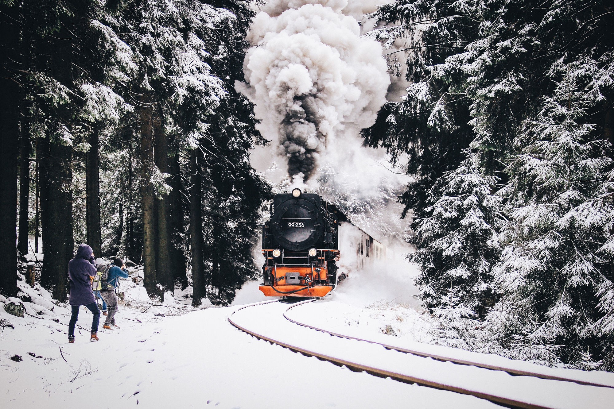 Steam train in a snowy forest with people HD Wallpaper