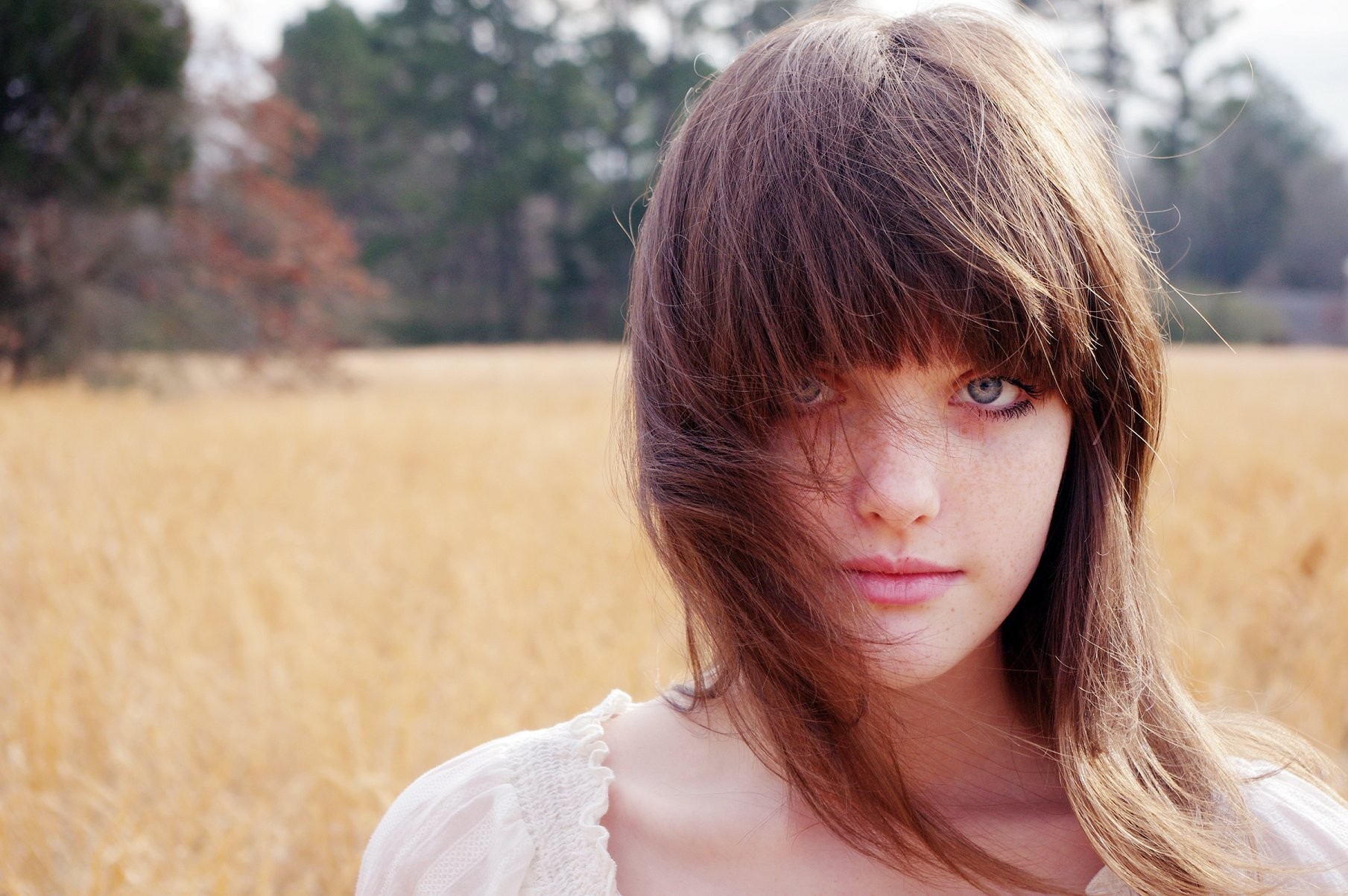 Woman with brown hair and blue eyes in a field HD Wallpaper