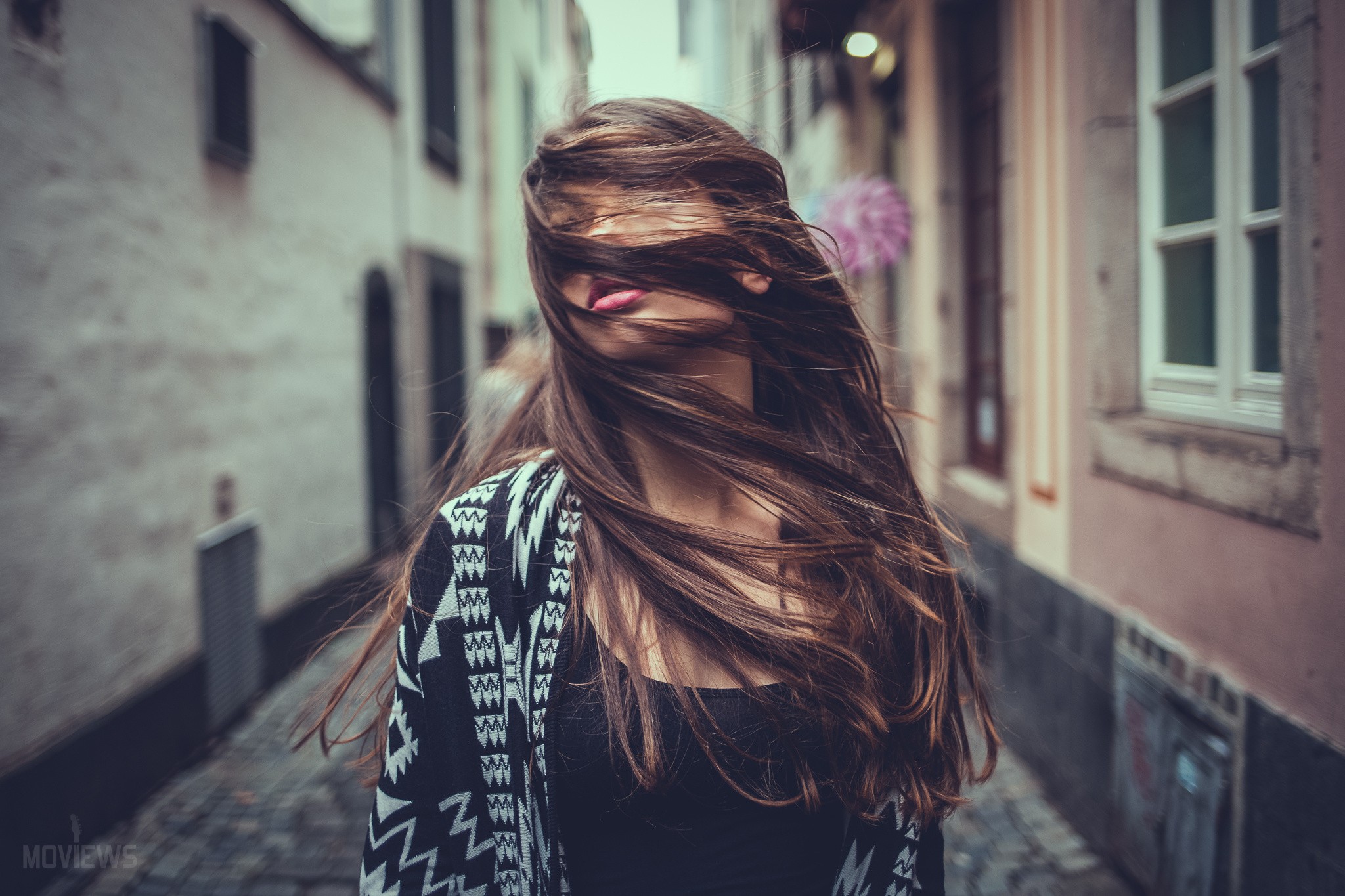 Woman with hair blowing in her face on a street HD Wallpaper