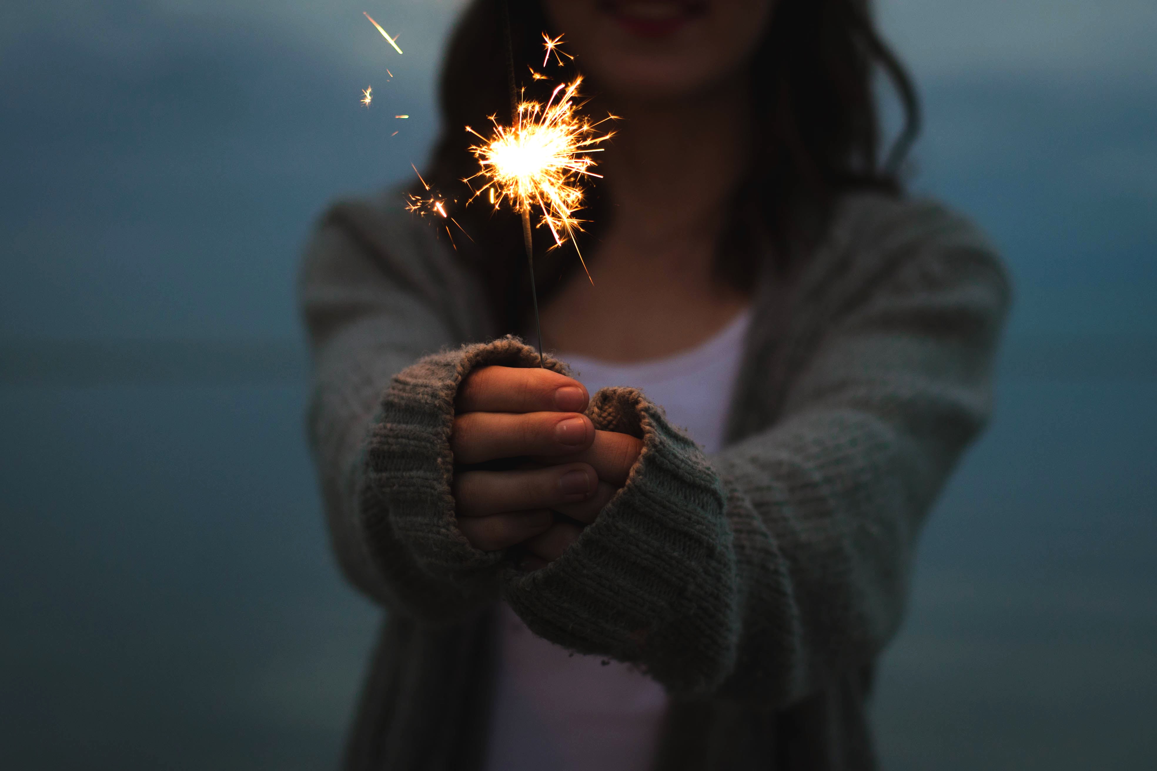 Woman holding a sparkler at dusk HD Wallpaper