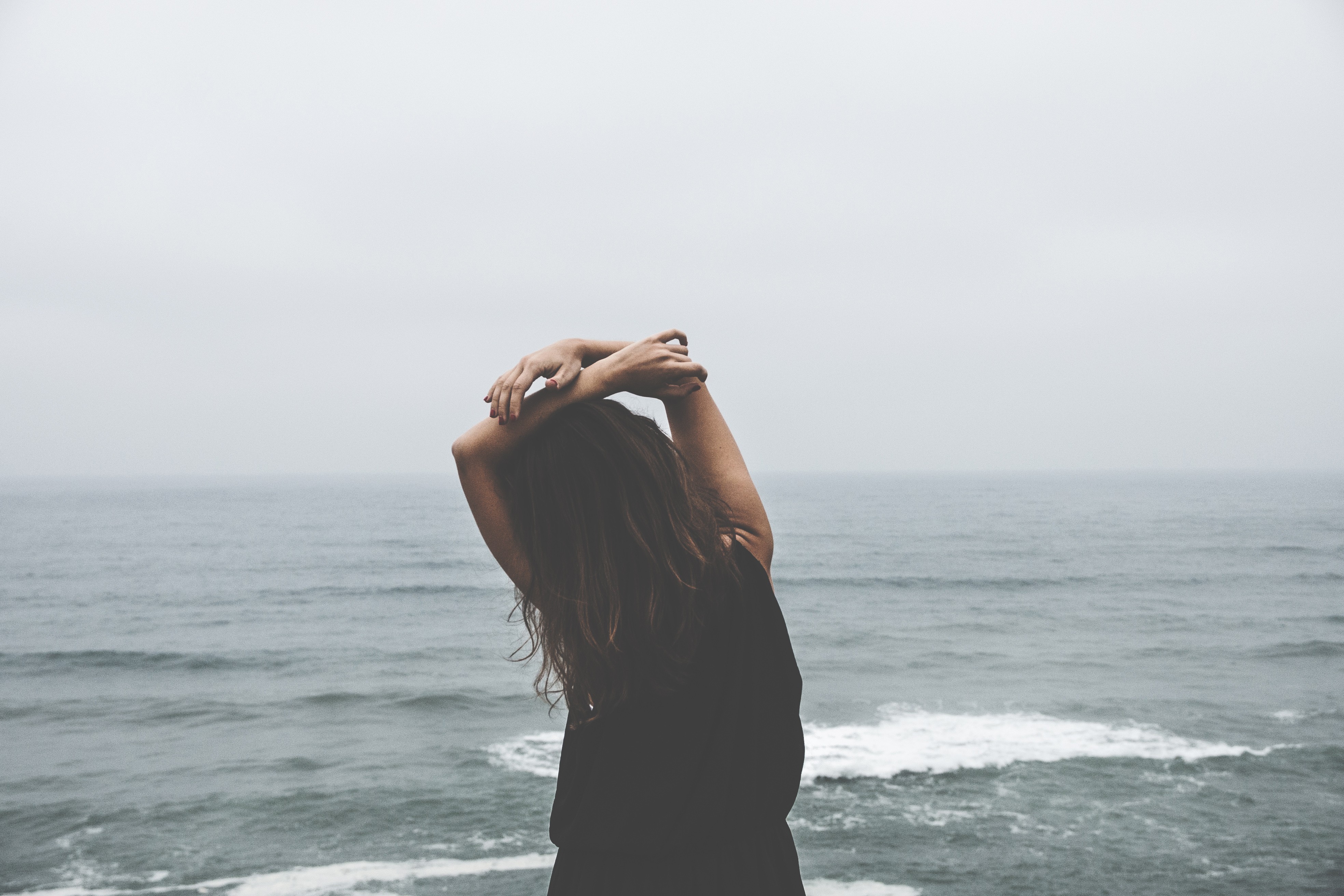 Woman with hands on head by the ocean HD Wallpaper