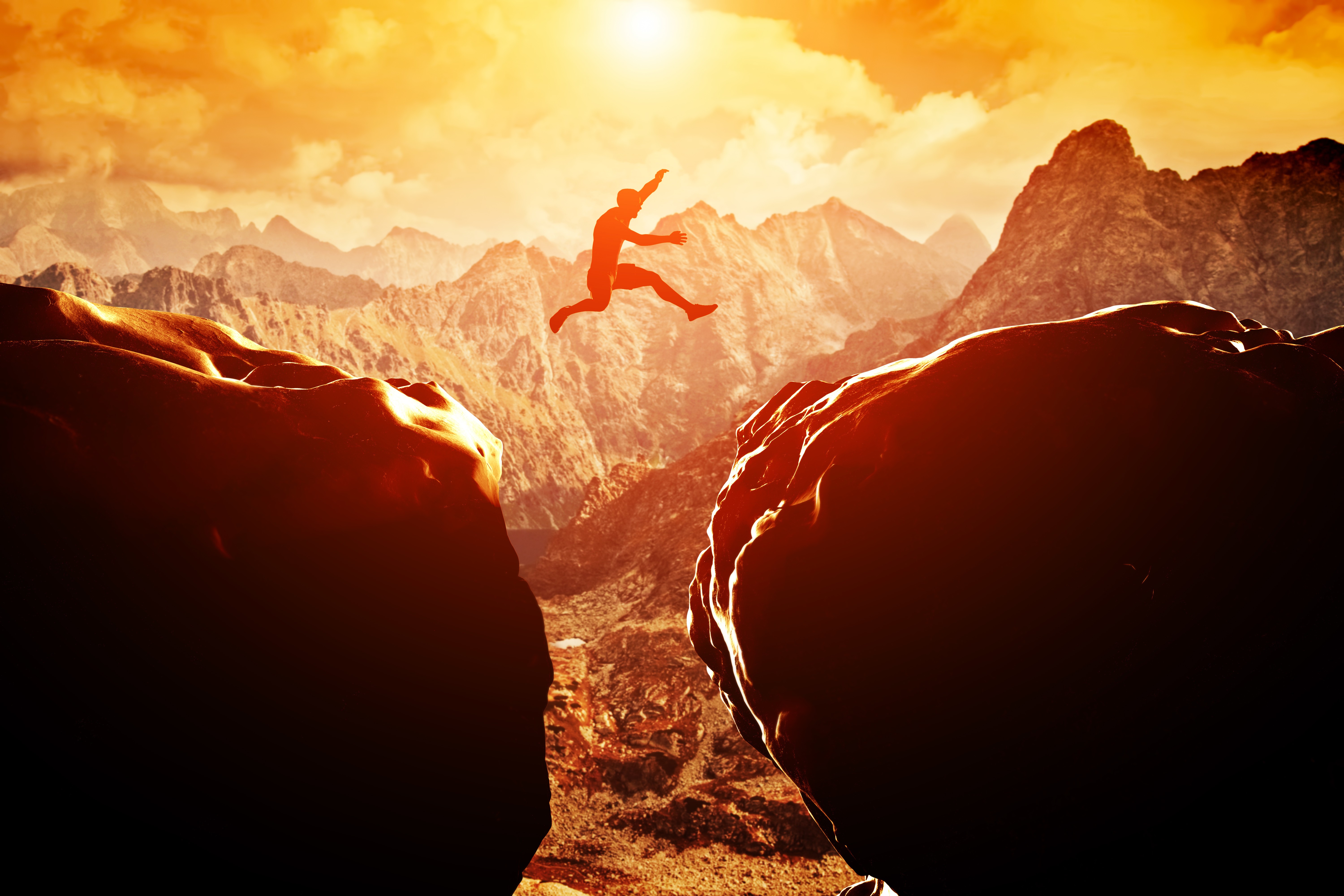 Silhouette of a person jumping across a mountain gap HD Wallpaper