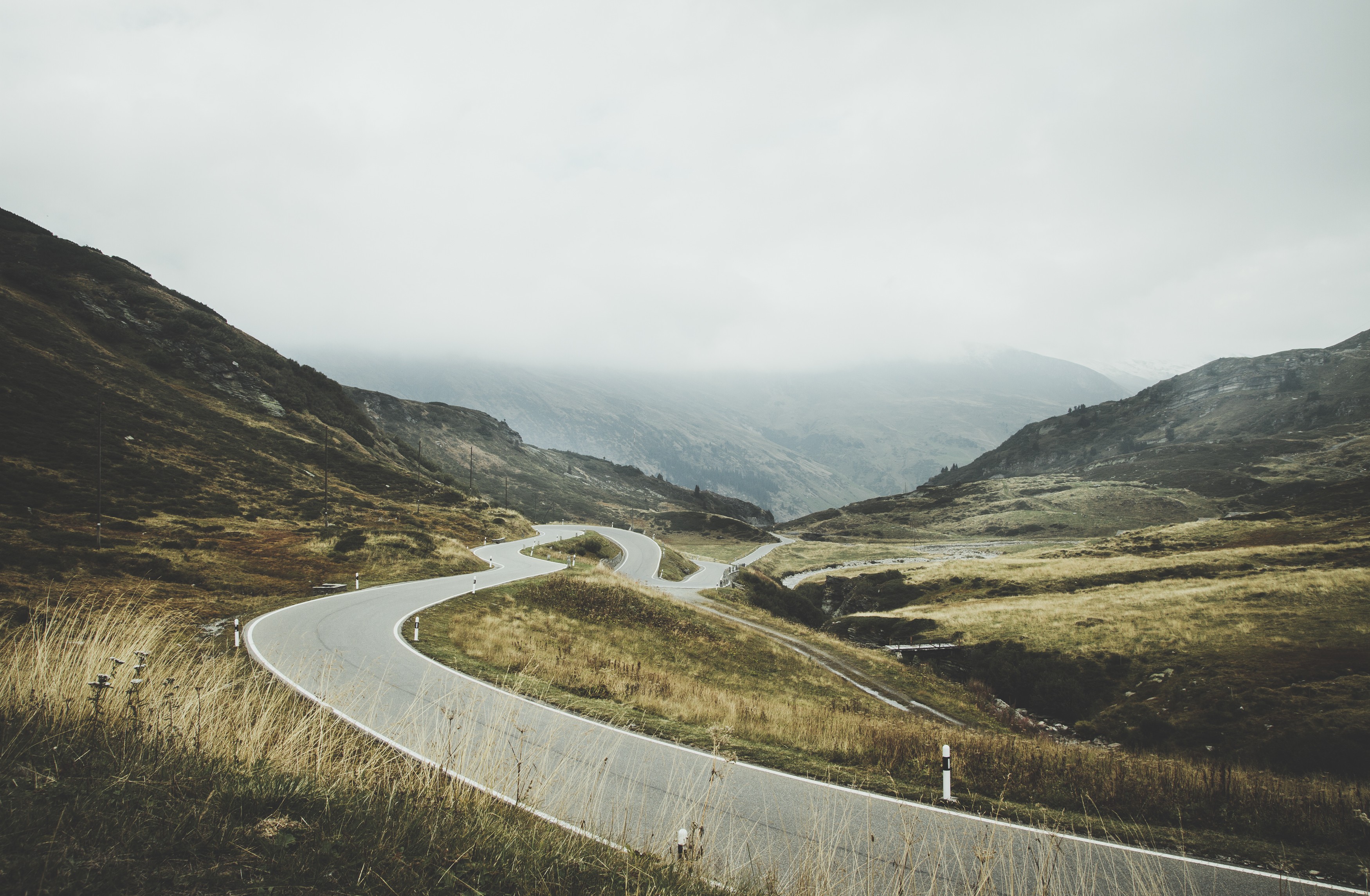 Winding mountain road through misty landscape HD Wallpaper