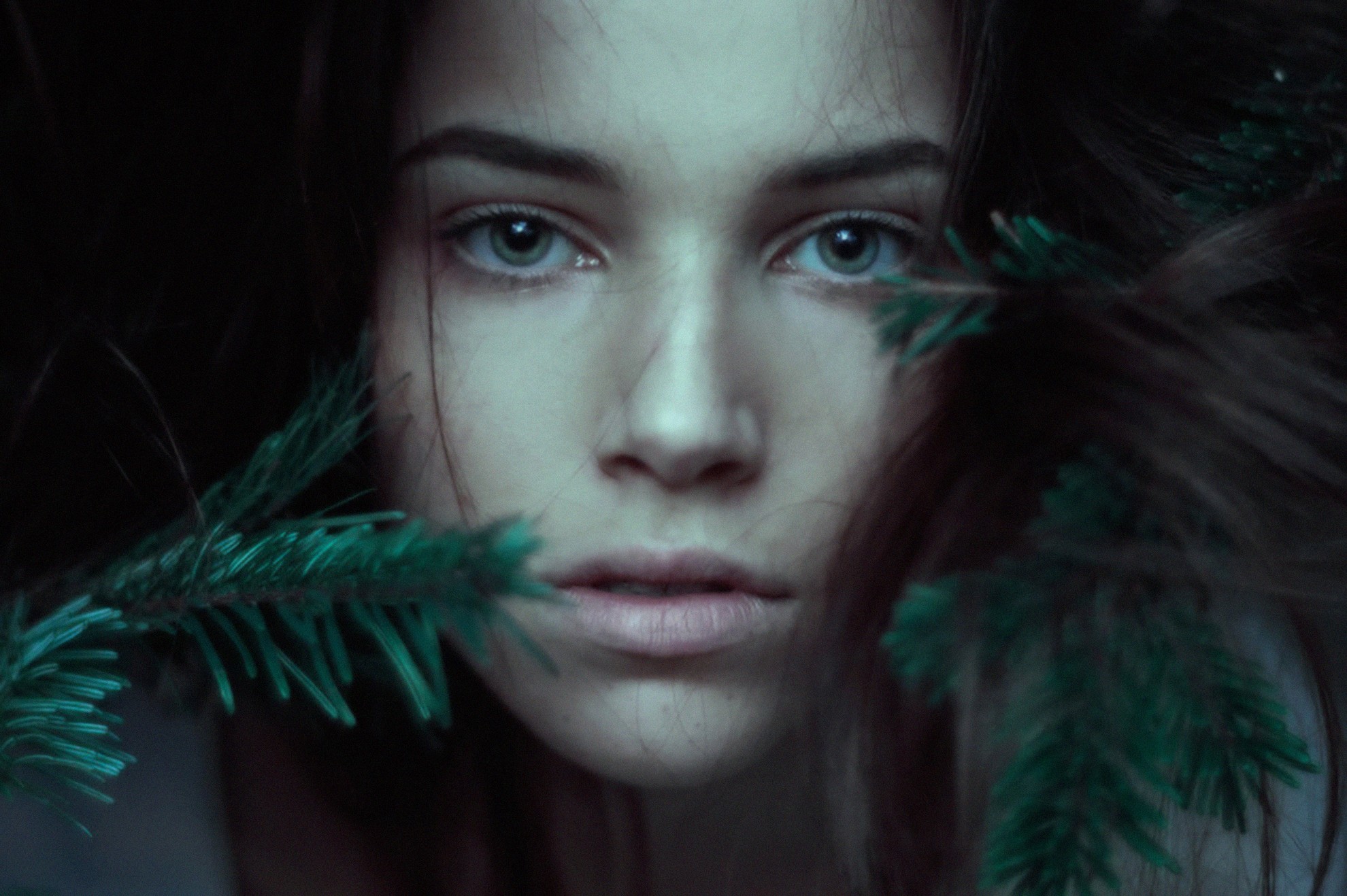 Close-up portrait of a young woman with pine branches HD Wallpaper