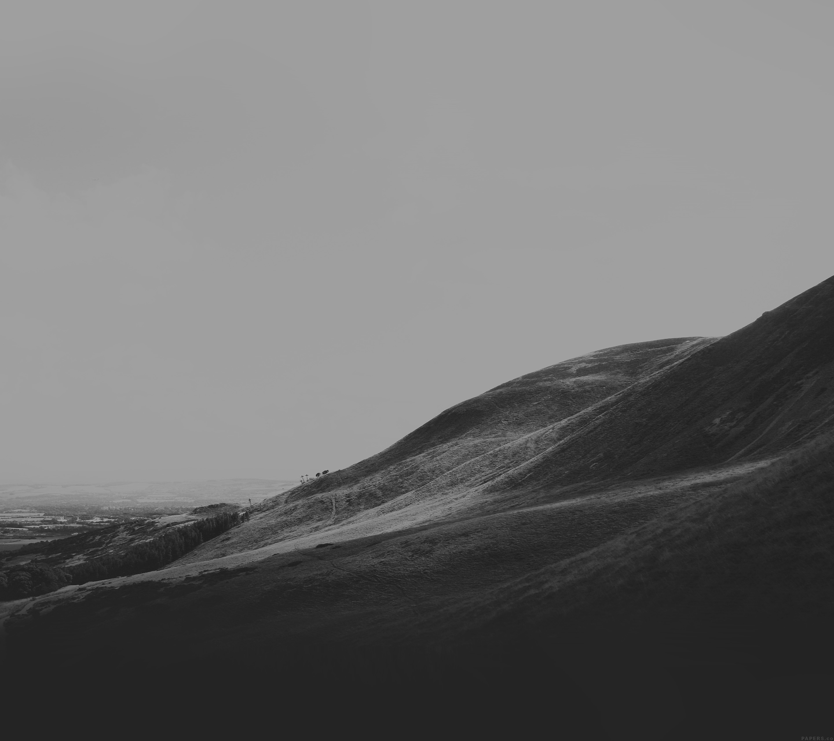 Monochrome landscape of rolling hills under a cloudy sky HD Wallpaper
