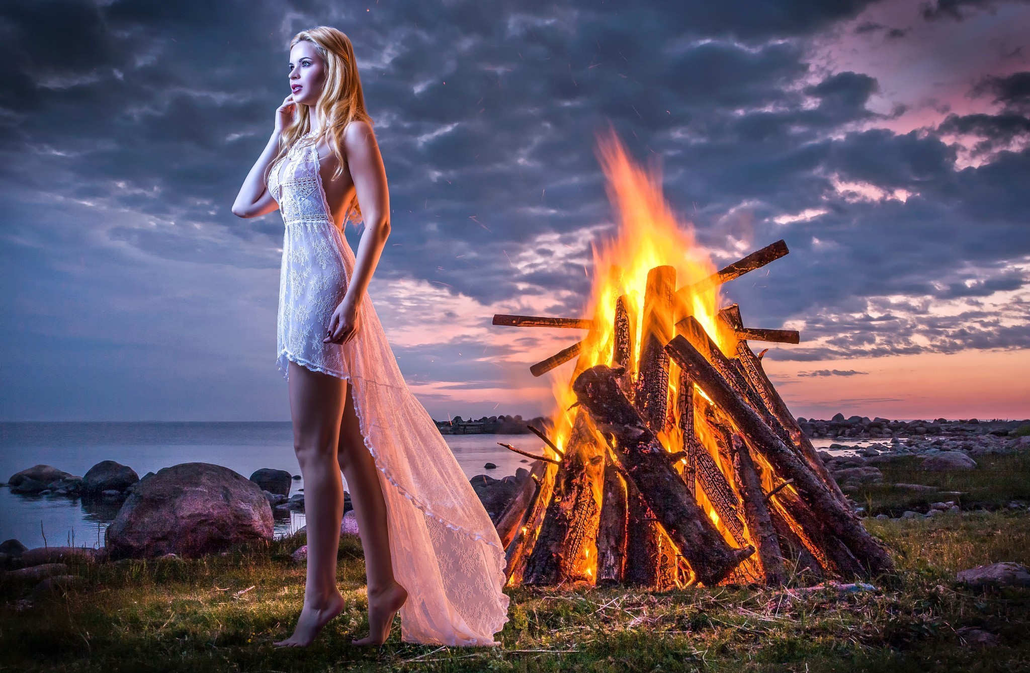 Woman in white dress by a bonfire at sunset HD Wallpaper