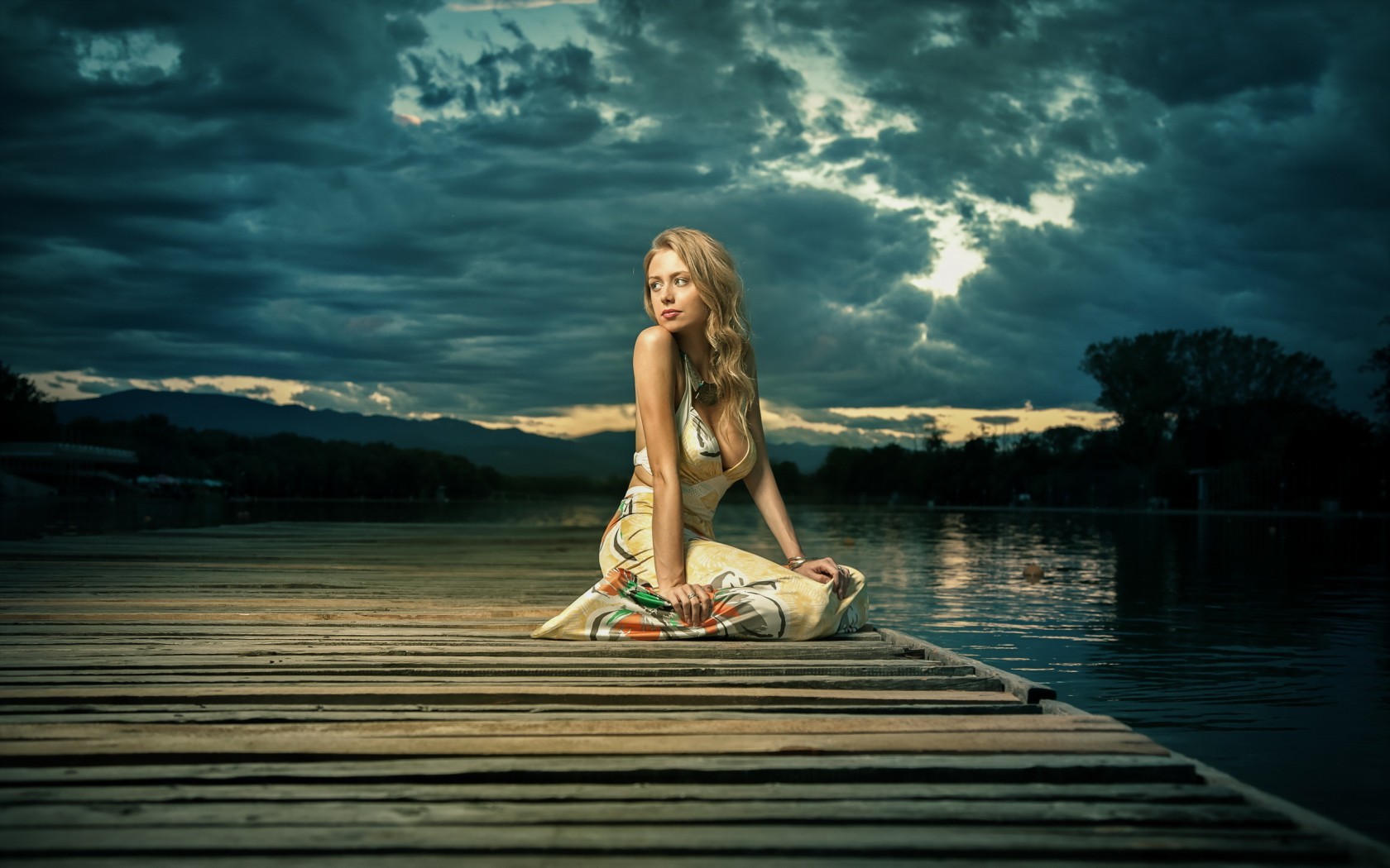 Woman in dress sitting on a wooden dock by the lake HD Wallpaper