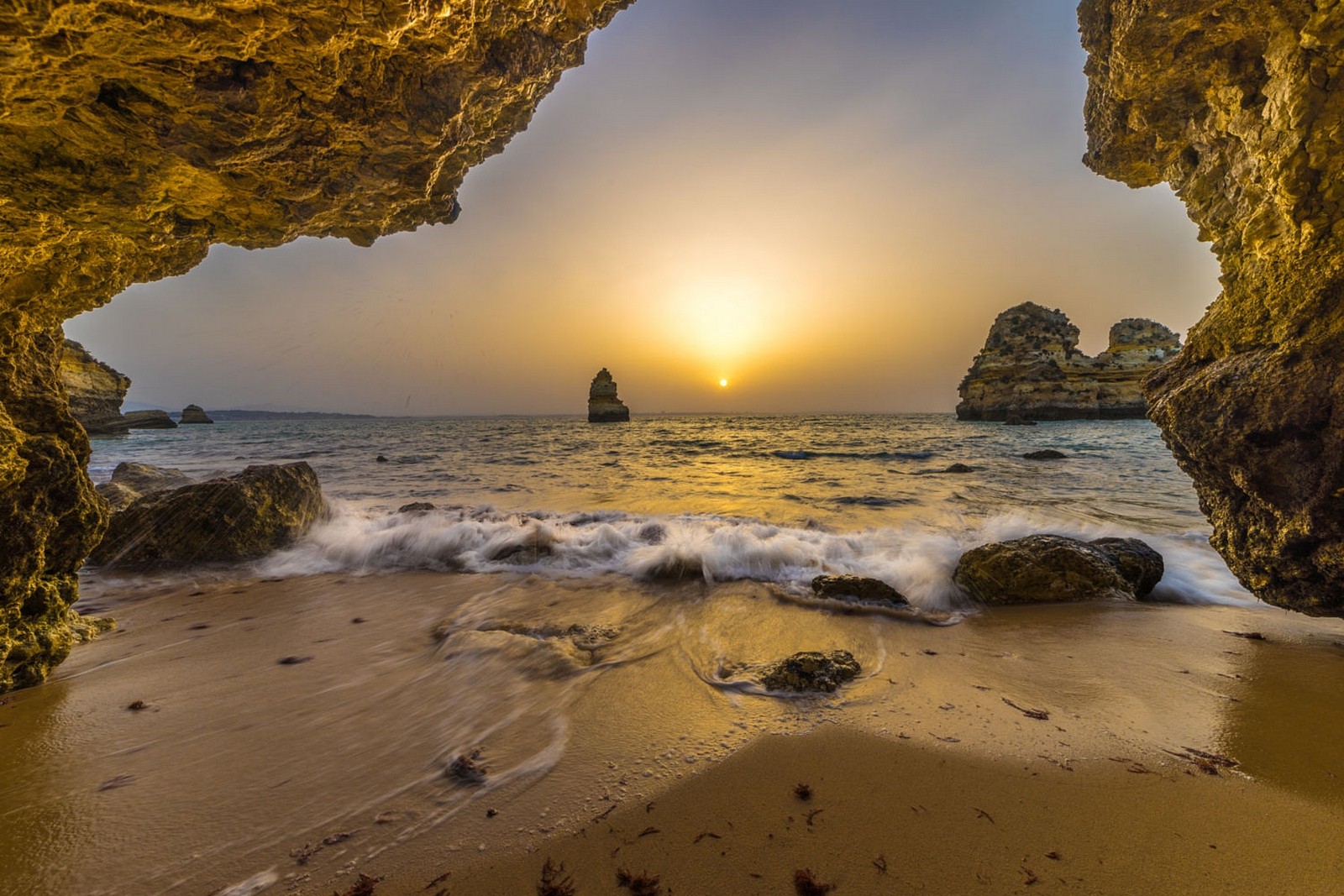 Sunset over the ocean seen from a cave in Portugal HD Wallpaper