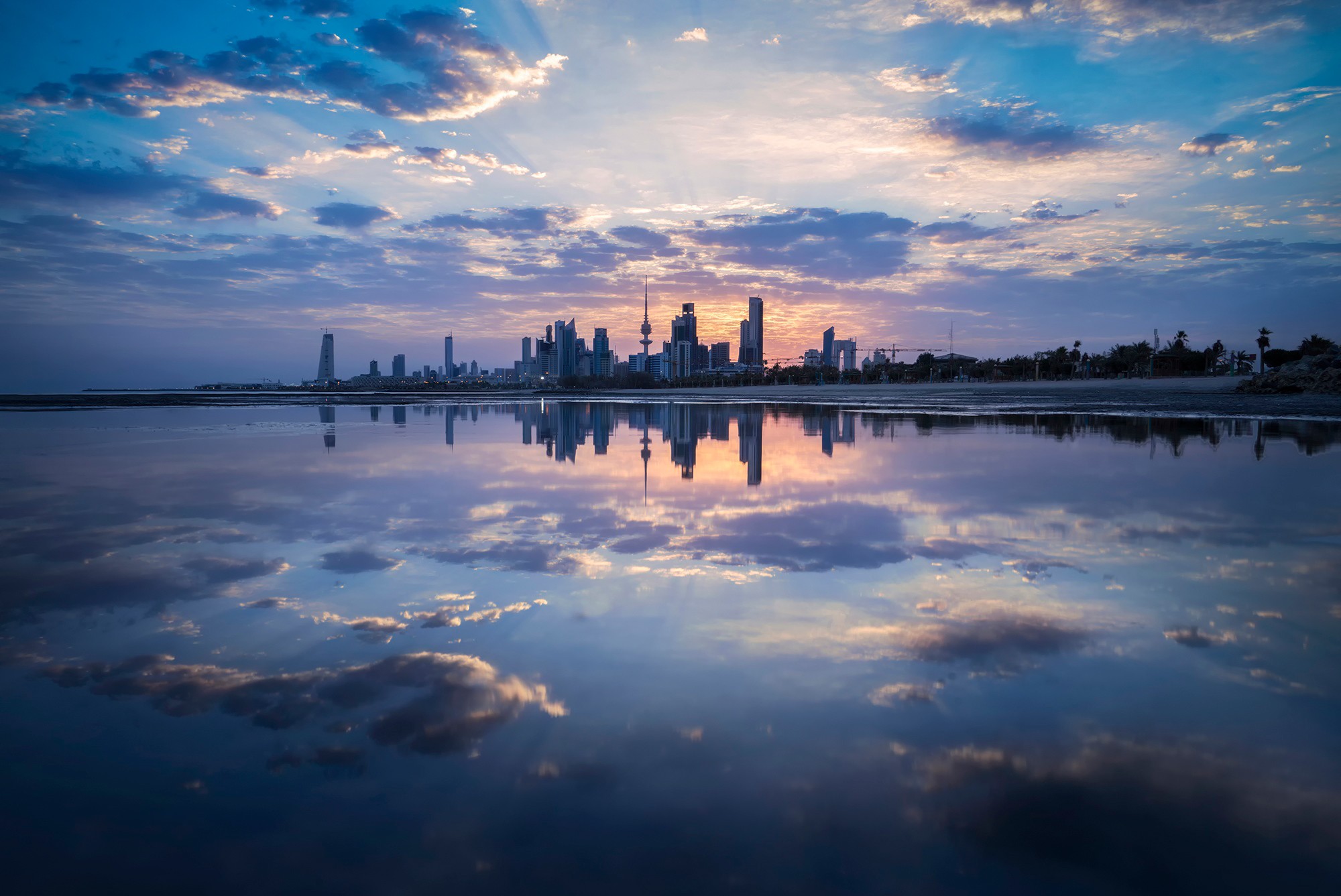 Kuwait City skyline reflected in water at sunset HD Wallpaper
