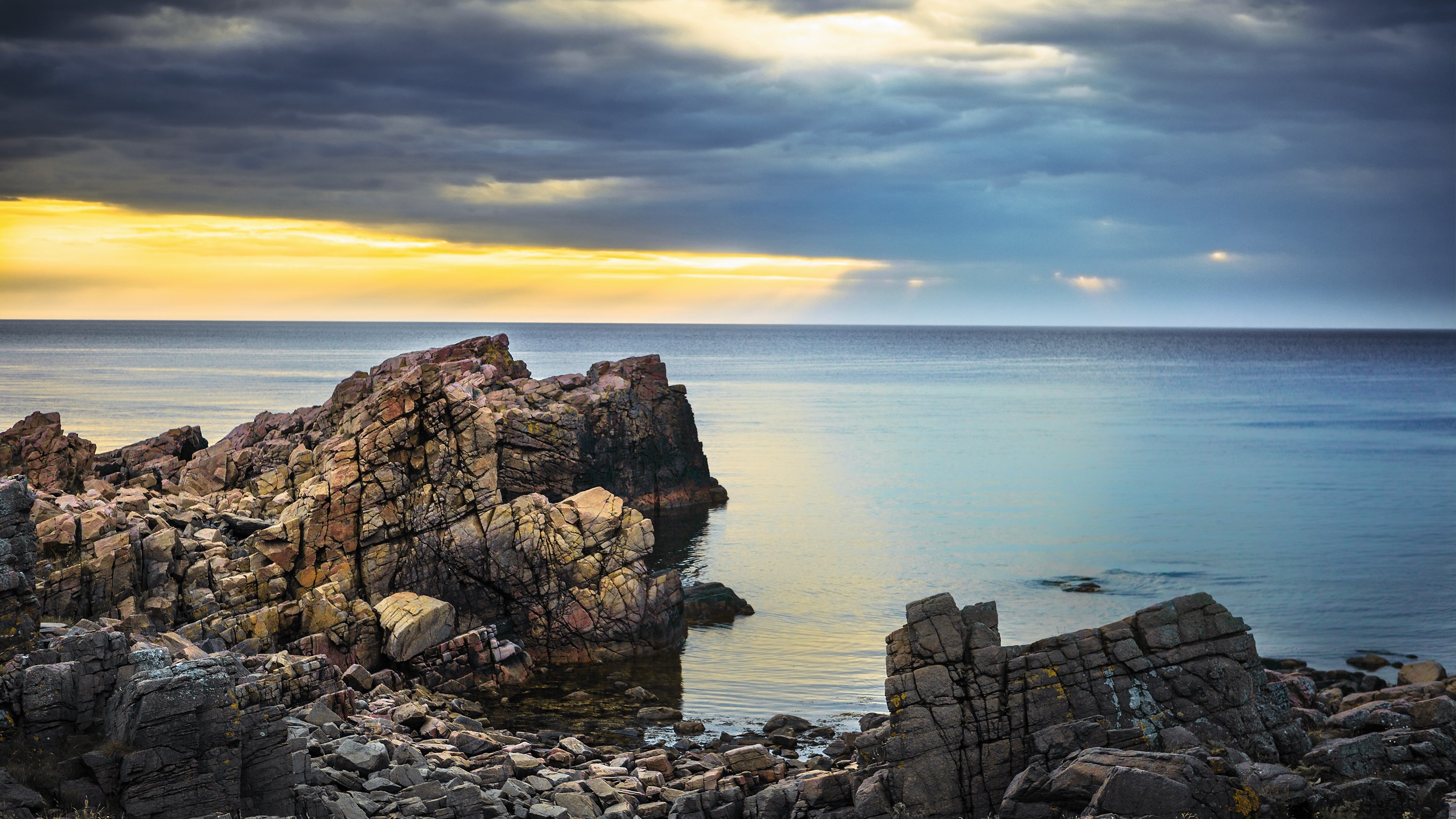 Rocky coastline with dramatic clouds over the sea HD Wallpaper