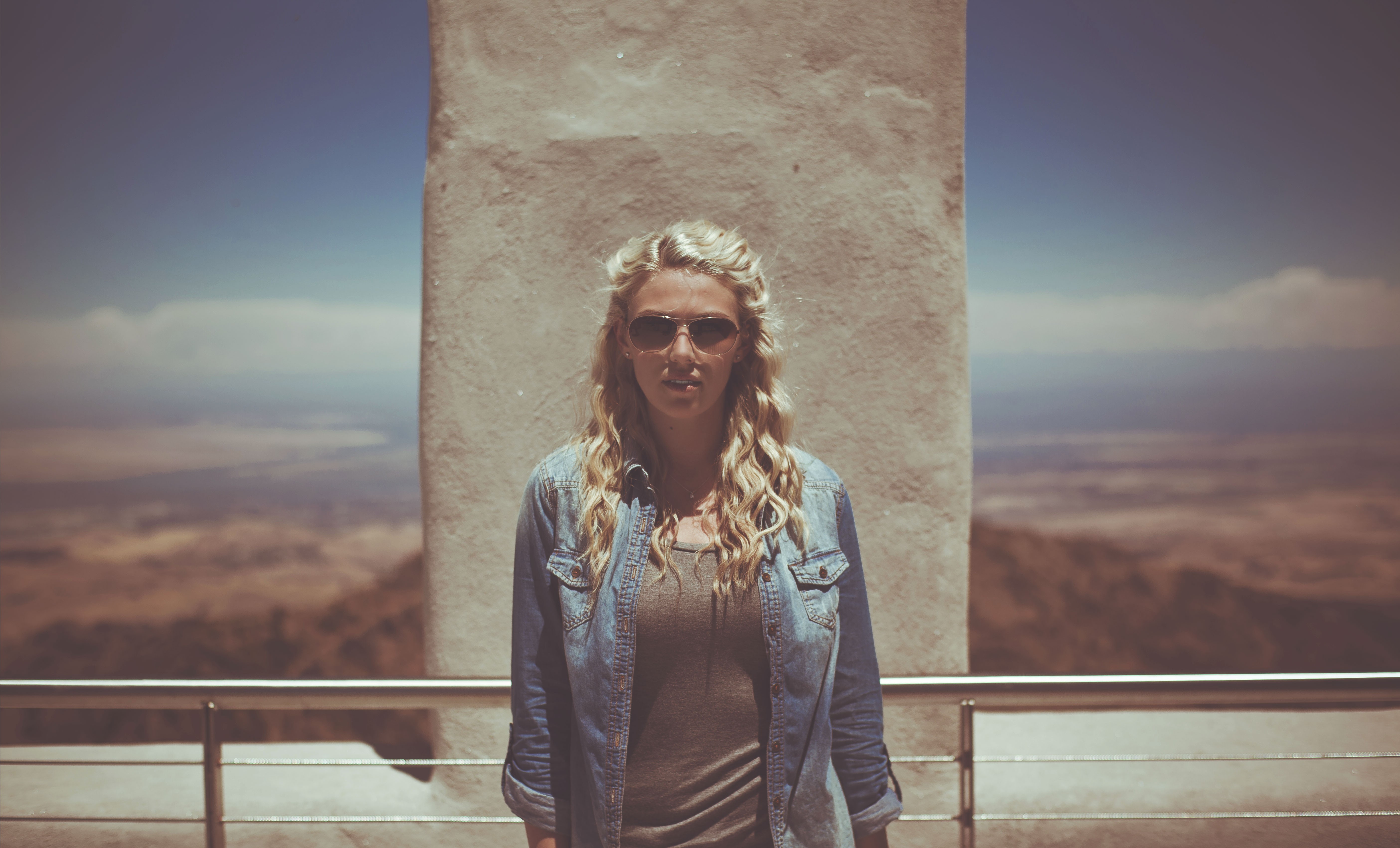 Woman with blonde curly hair wearing sunglasses and denim jacket HD Wallpaper
