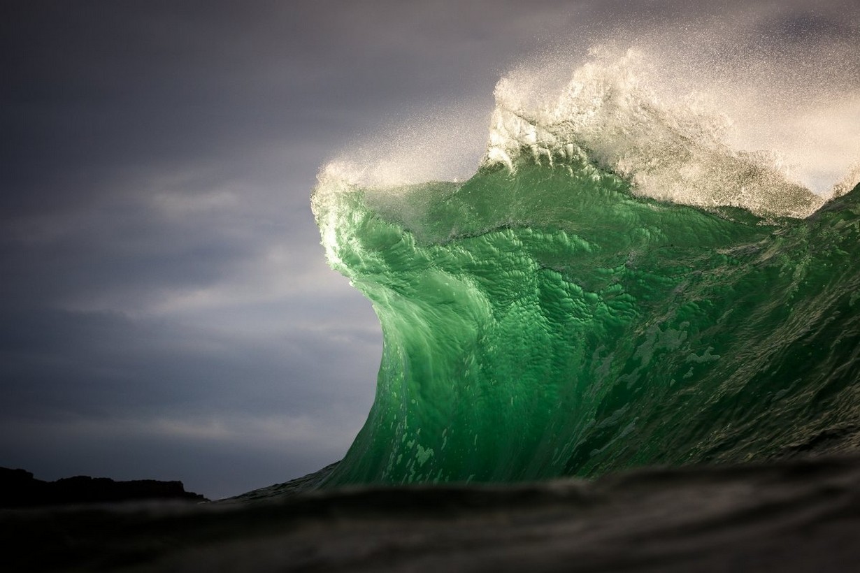 Green wave crashing under a cloudy sky HD Wallpaper