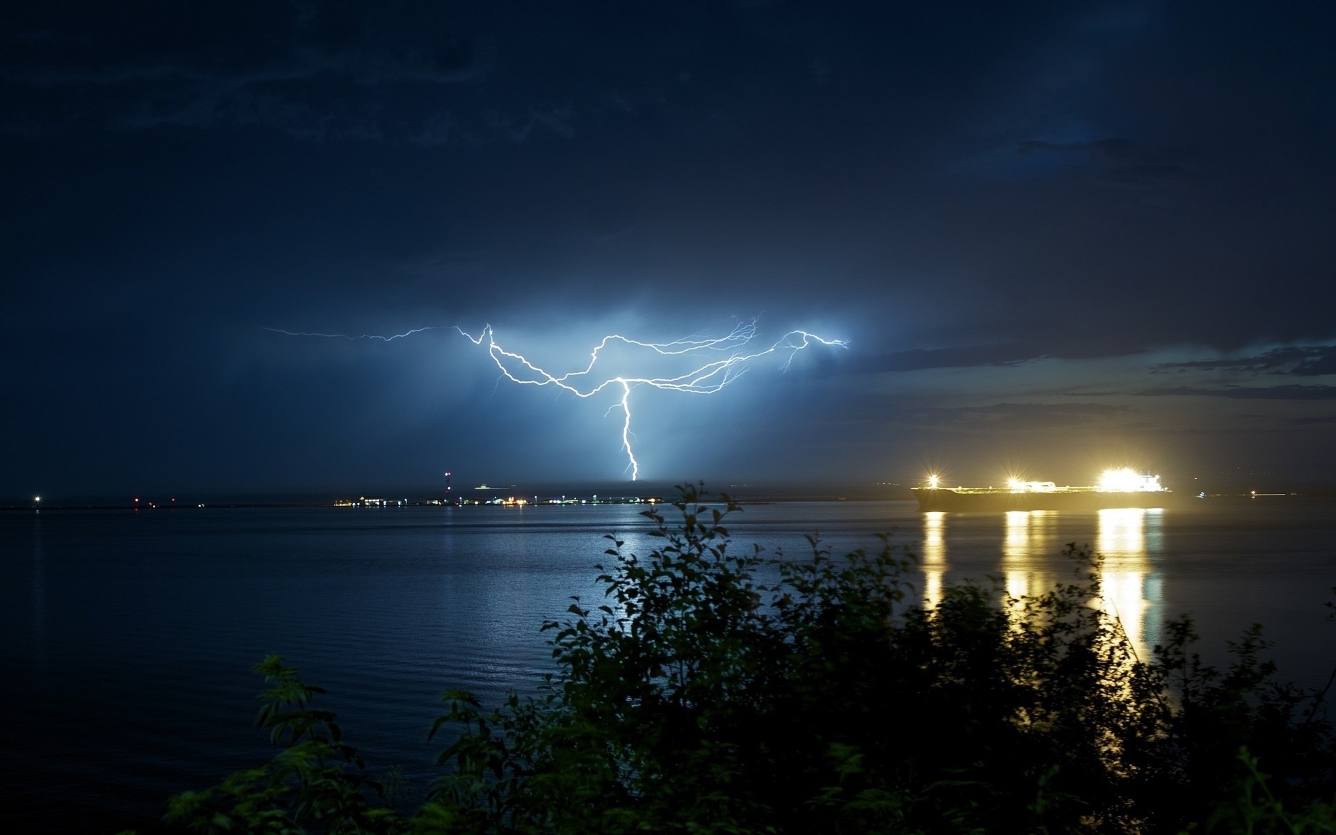 Lightning strikes over a body of water at night HD Wallpaper
